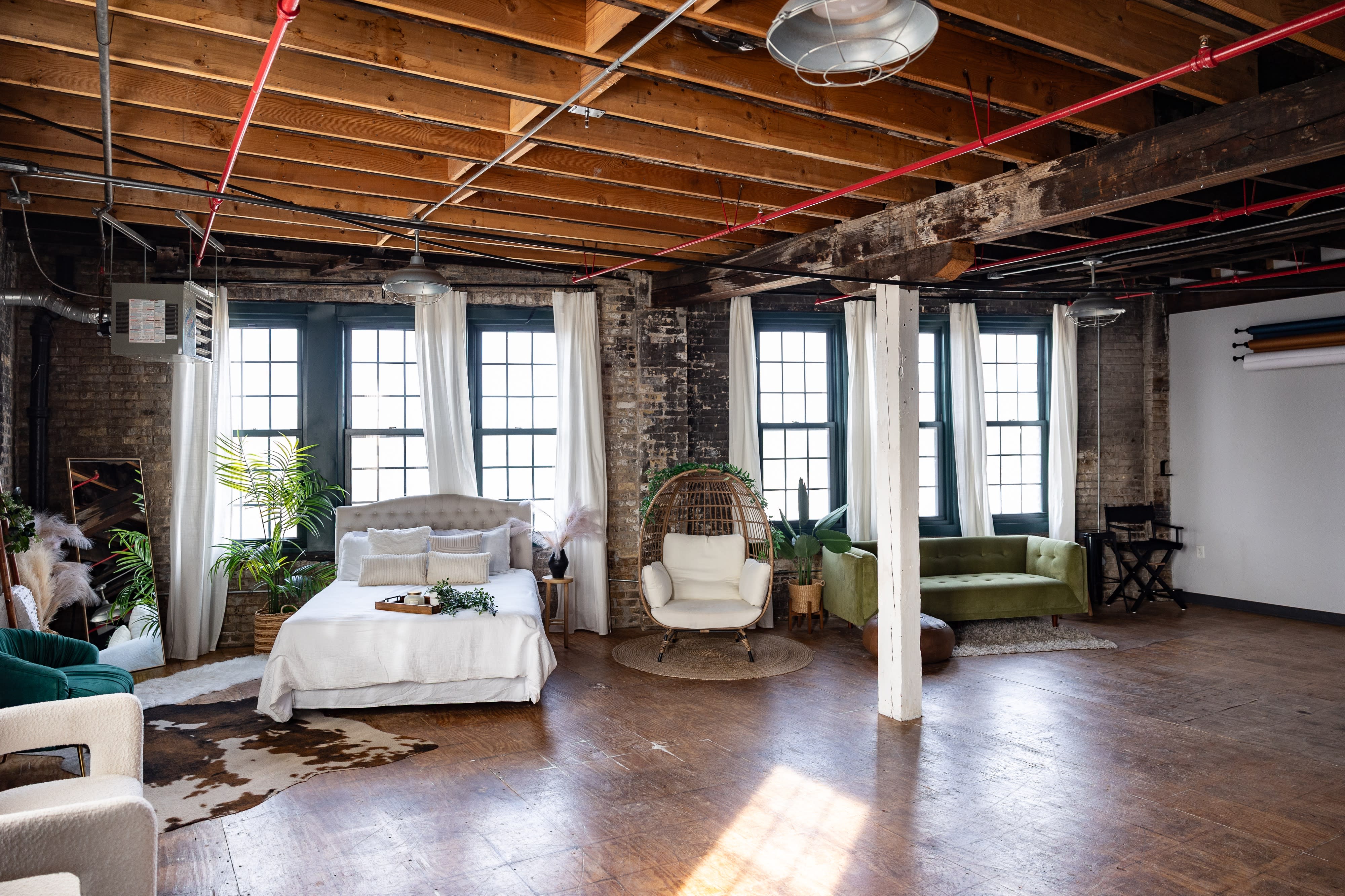 A video shoot takes place in a spacious, well-lit loft with large windows, featuring a dining table and a cozy seating area.