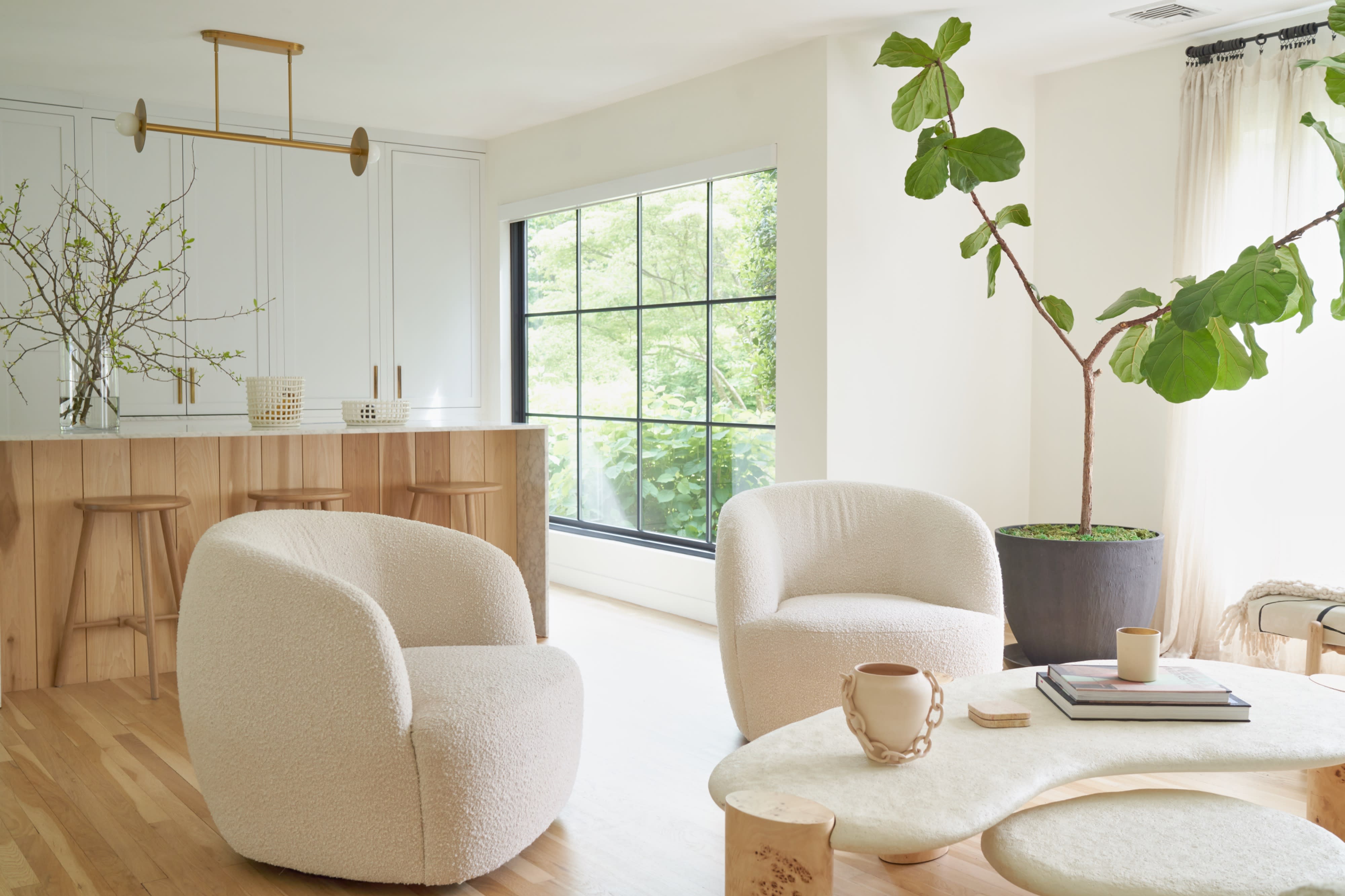 Four individuals are seated in modern armchairs within a well-lit, contemporary living space, all dressed in formal attire.