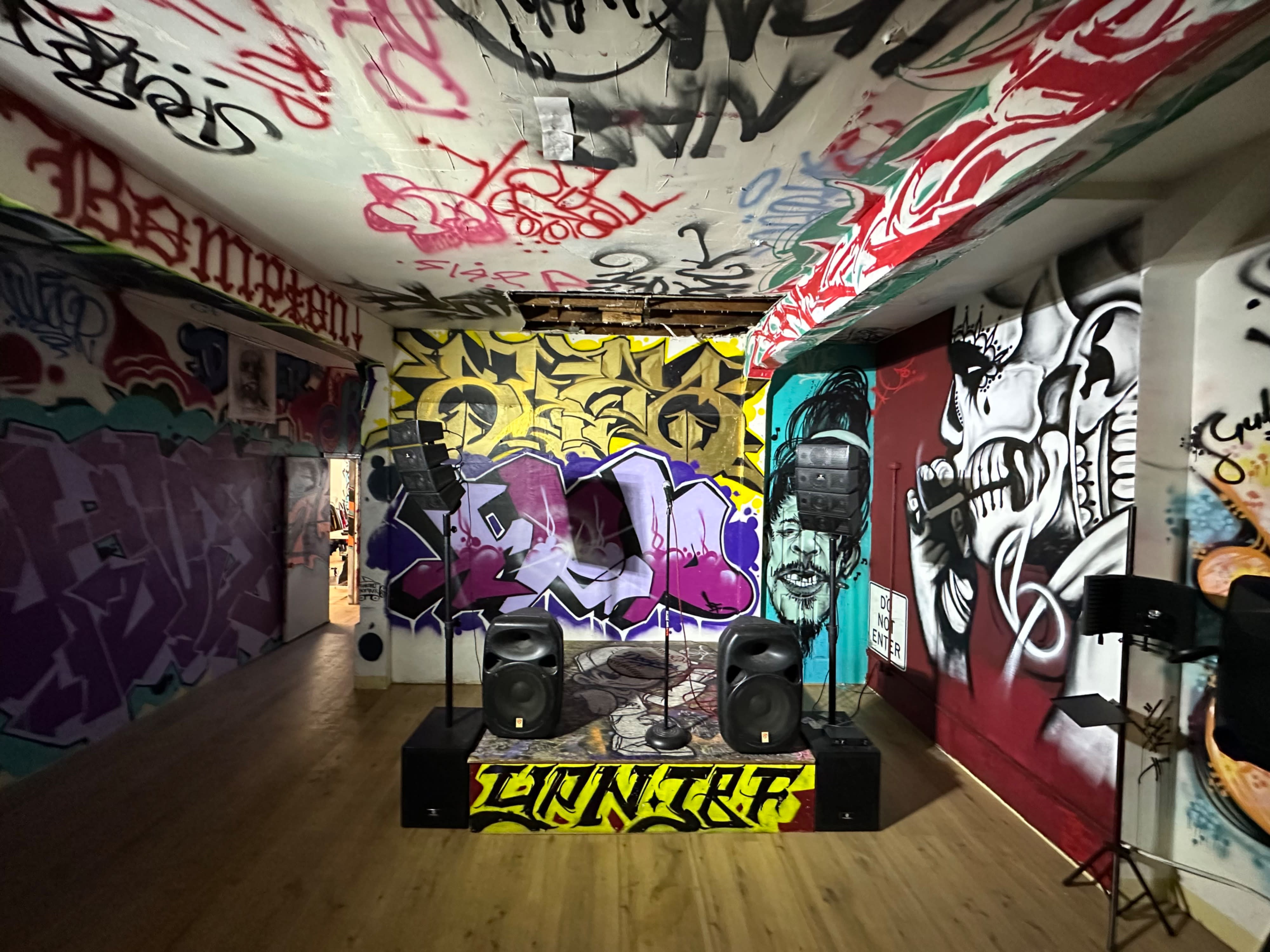A large group of people poses together in a graffiti-adorned space after an event.