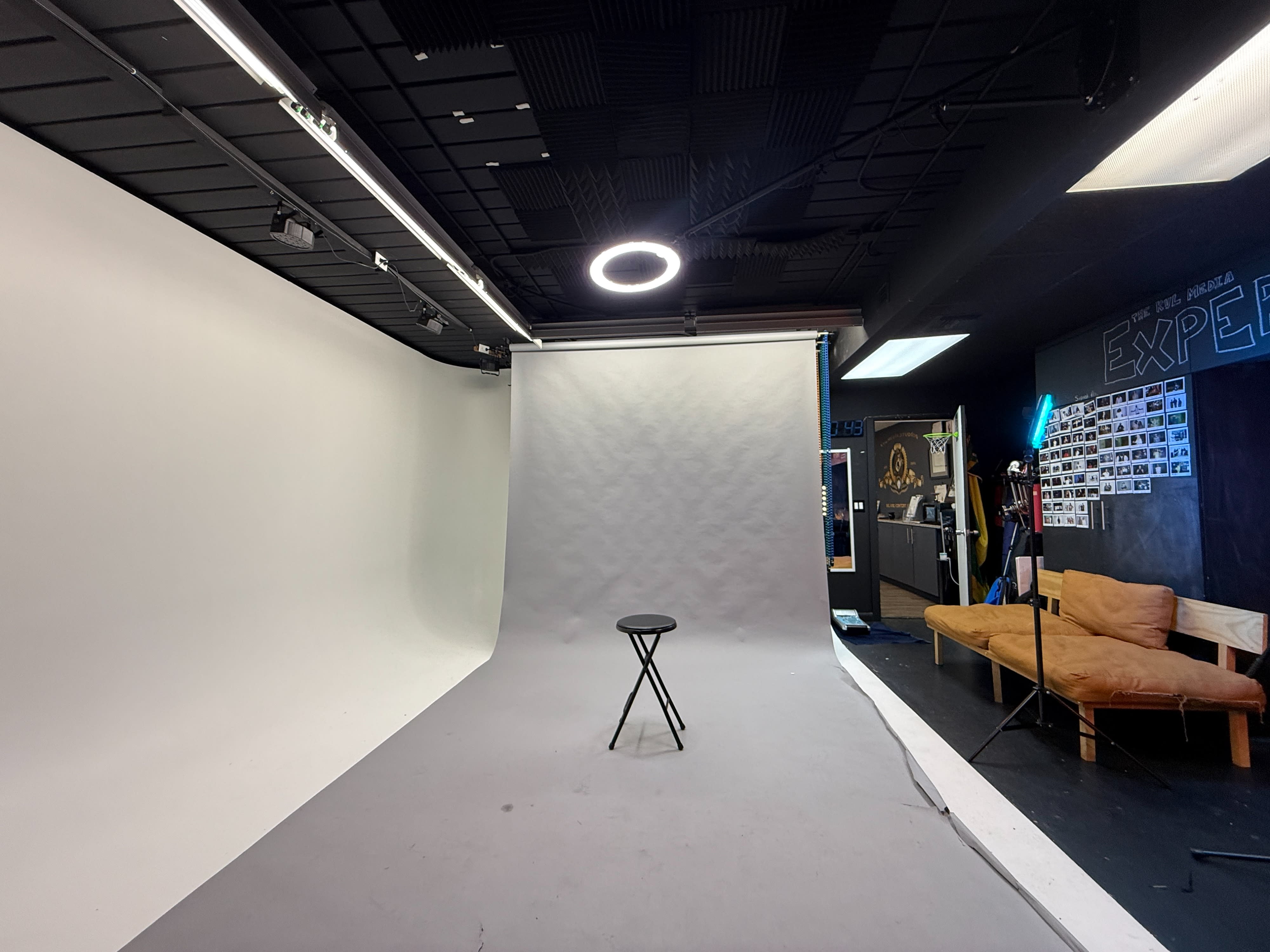 A photographer captures a posed photoshoot of two models in a studio with a plain backdrop.
