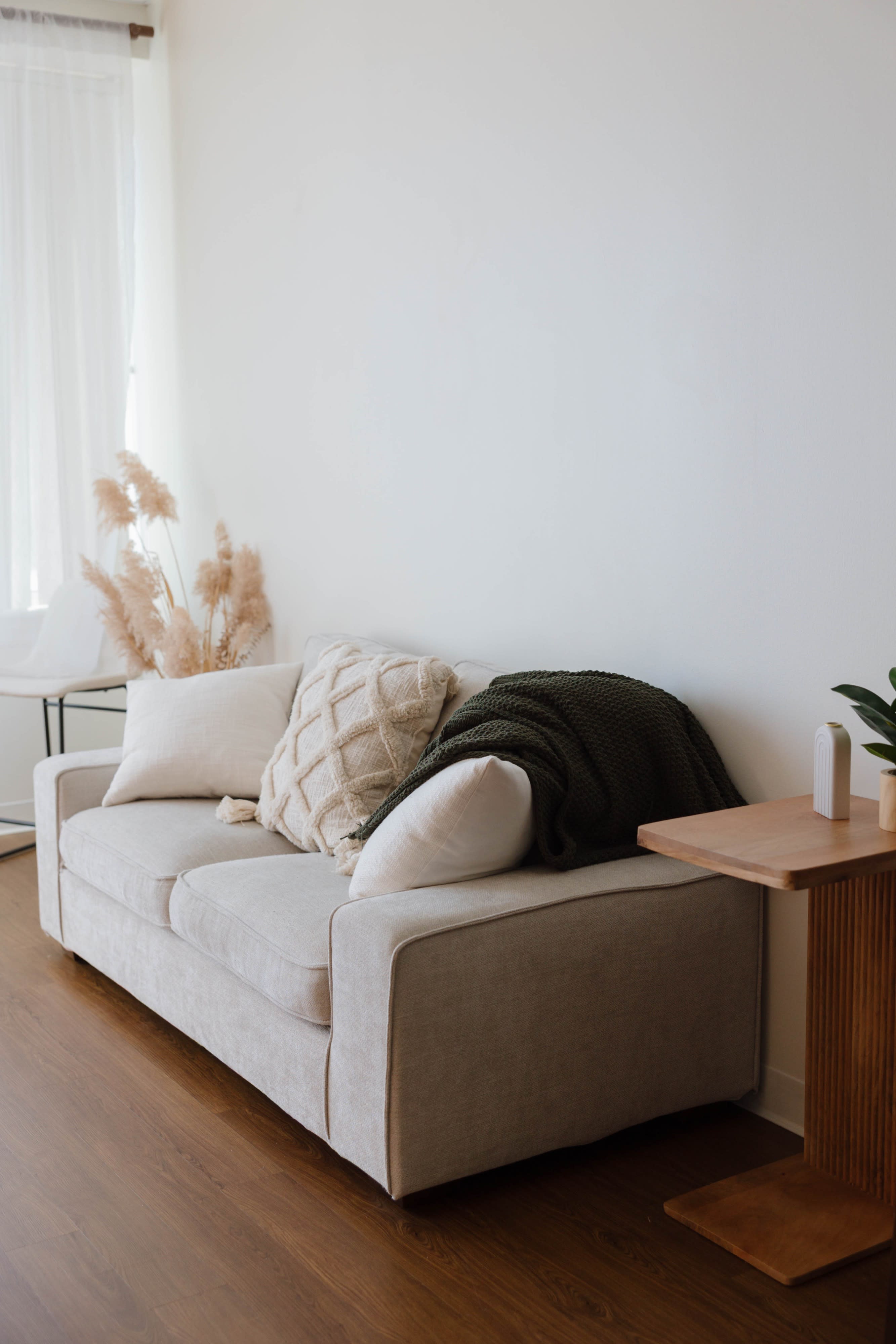 A spacious room features a bed with white bedding, natural light streaming through large windows, and a cozy seating area with unique furniture.