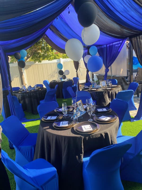 A colorful birthday party setup features a decorative arch with balloons and a large sign celebrating "Davina's Sweet One," complemented by oversized dessert-themed props.