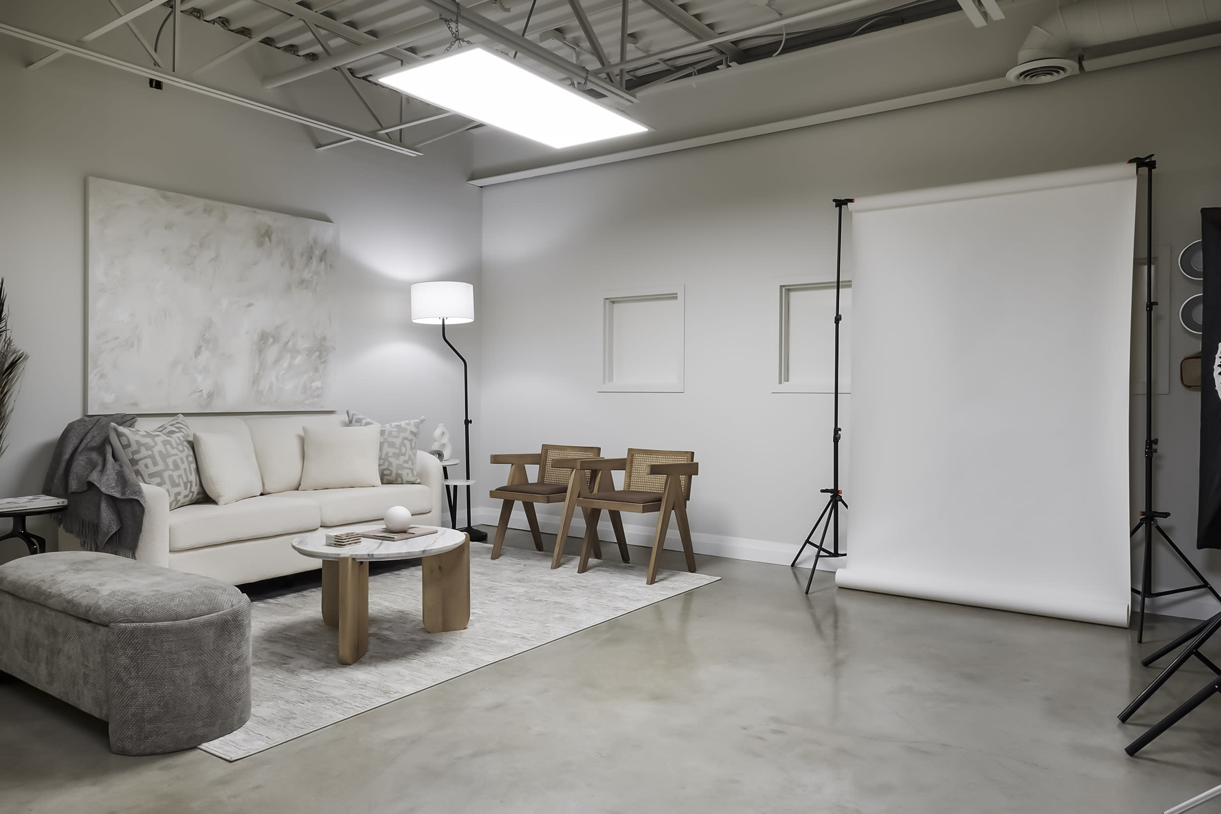 A model poses in a studio setting while a photographer directs the shoot with professional lighting equipment.