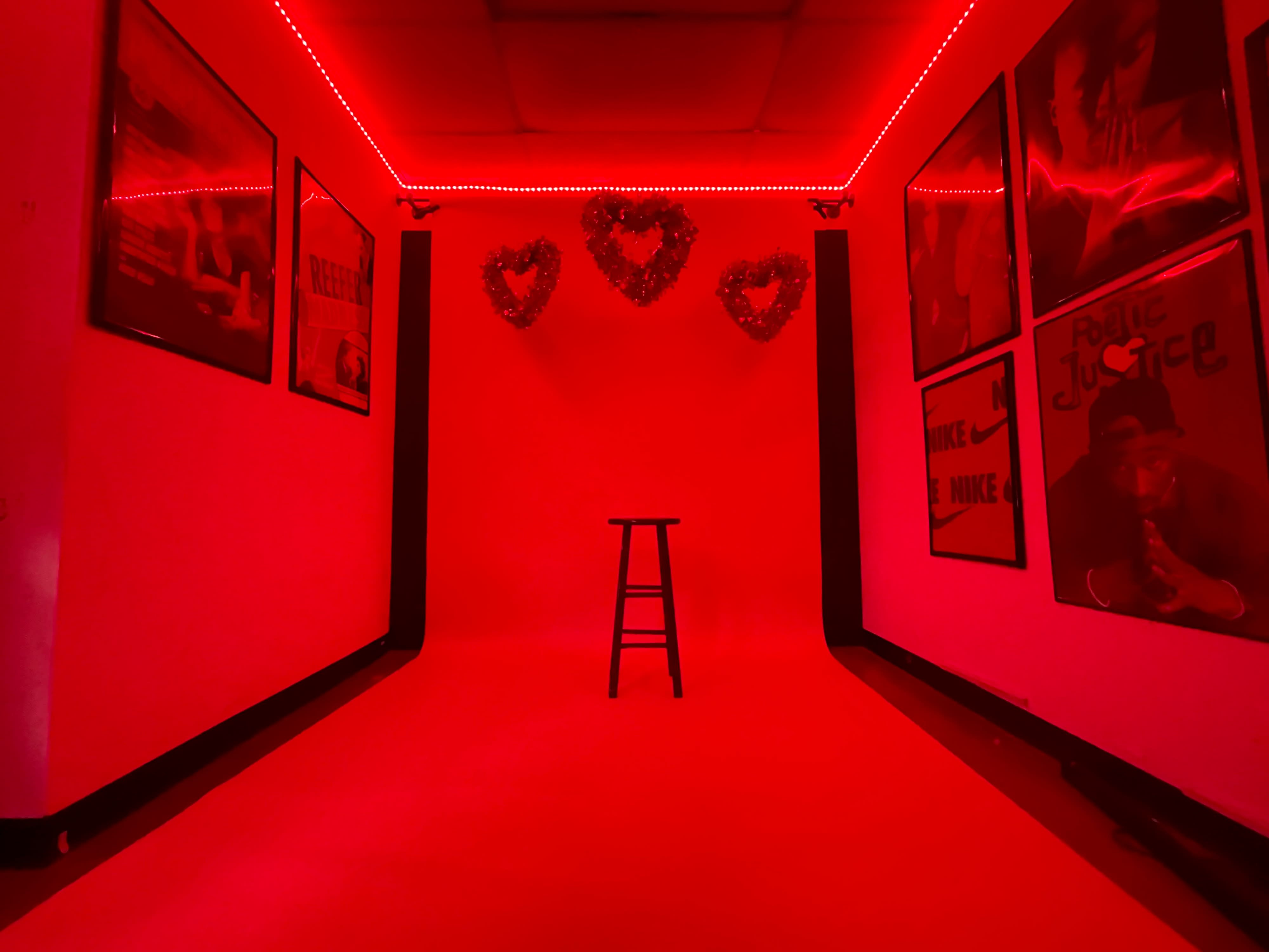 A model poses against a red backdrop adorned with heart decorations during a photoshoot.