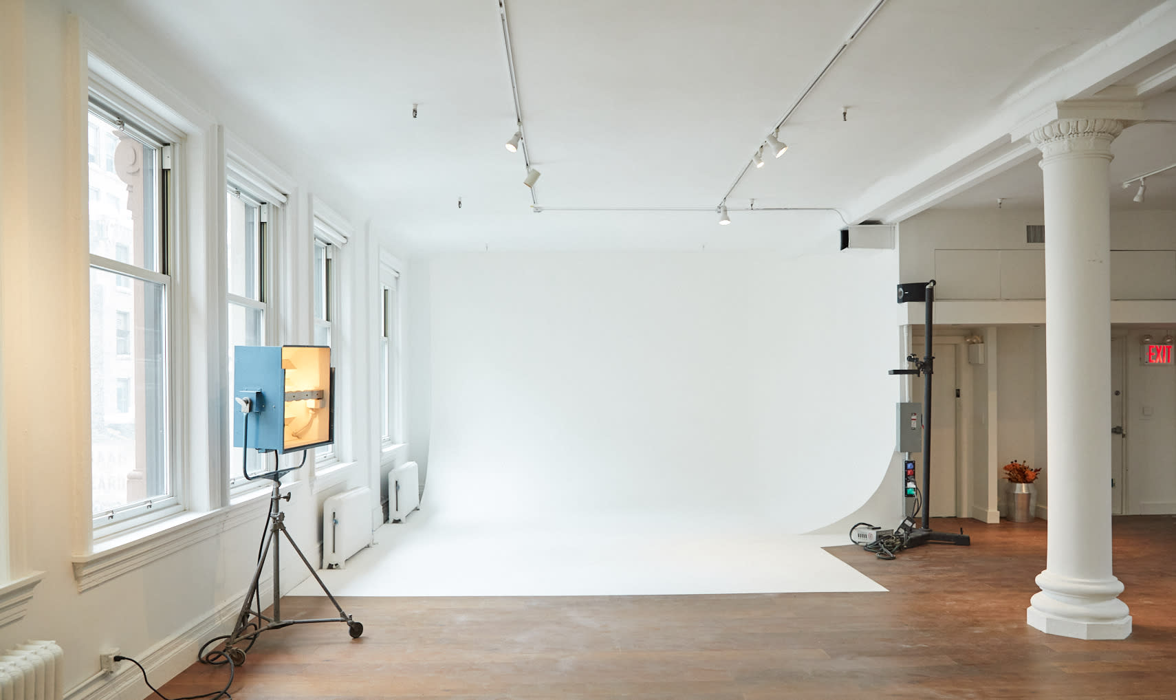 A person adjusts their hair while standing in a well-lit studio space.