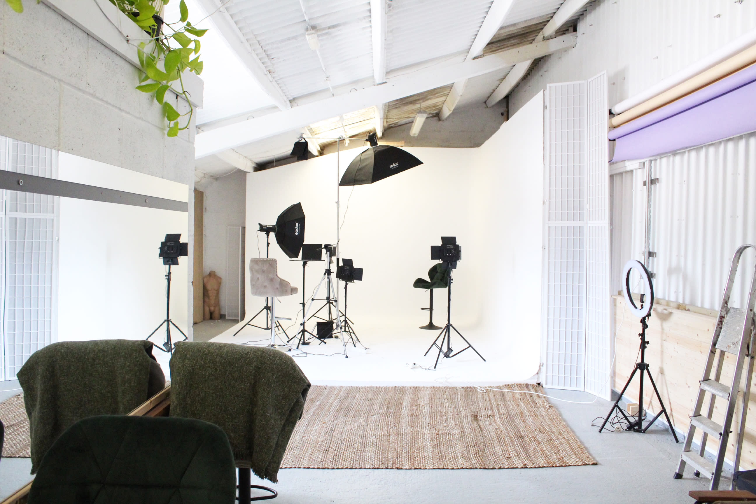 A man sits in a studio wearing a green suit, preparing for a photo shoot.