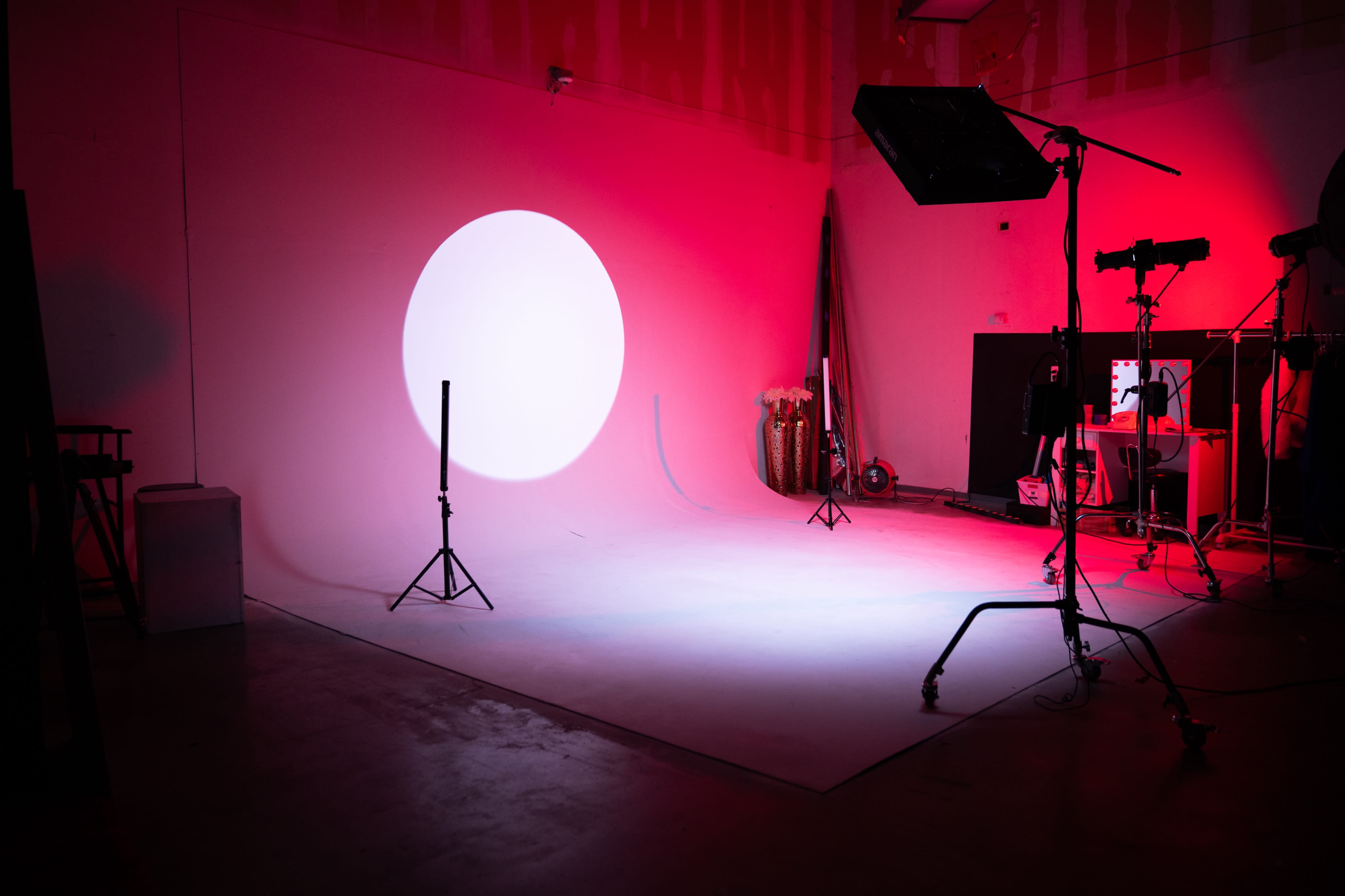 A model poses on a chair under dramatic lighting during a photoshoot.