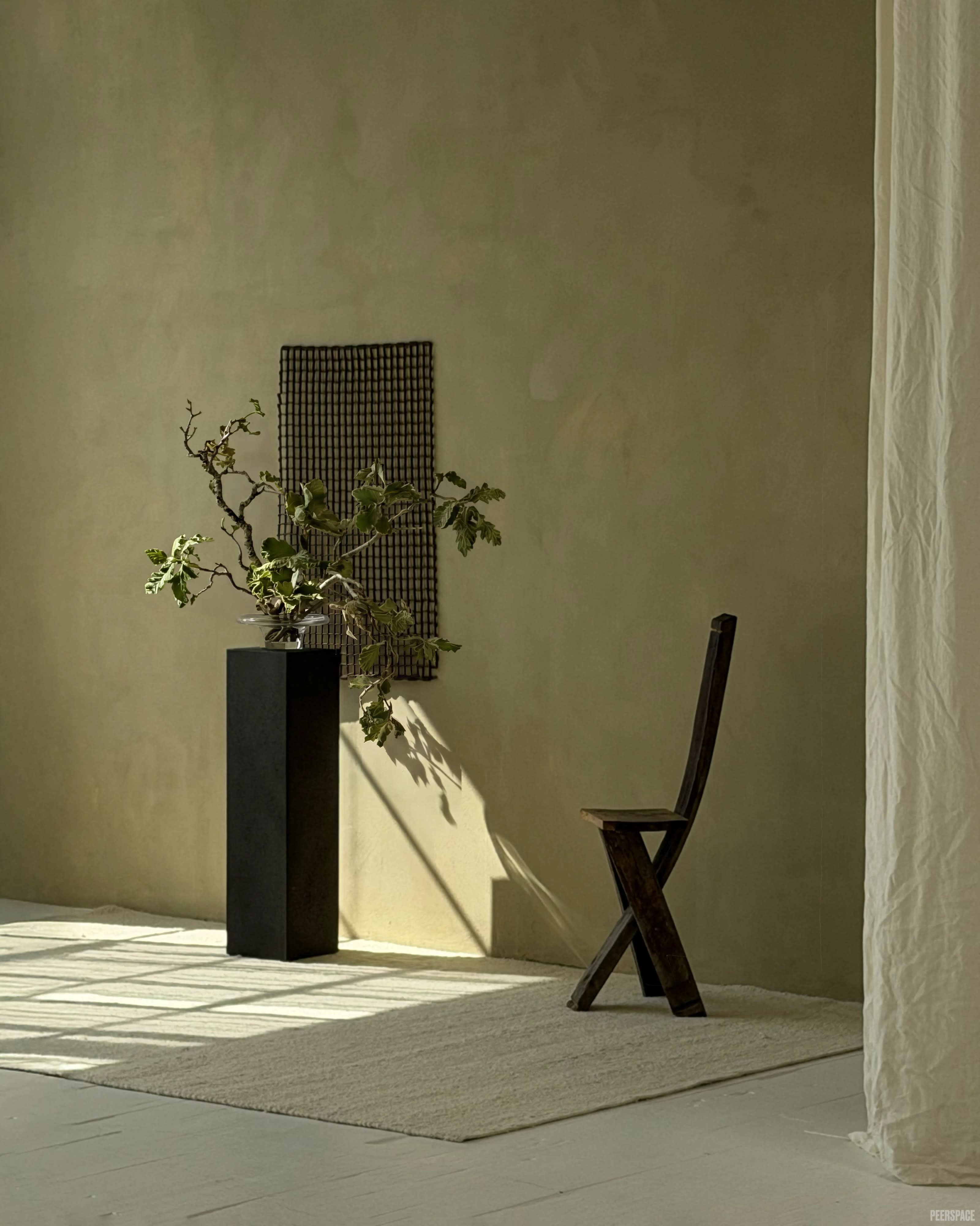 A person sits on a couch, positioned in natural light that casts shadows across the room.