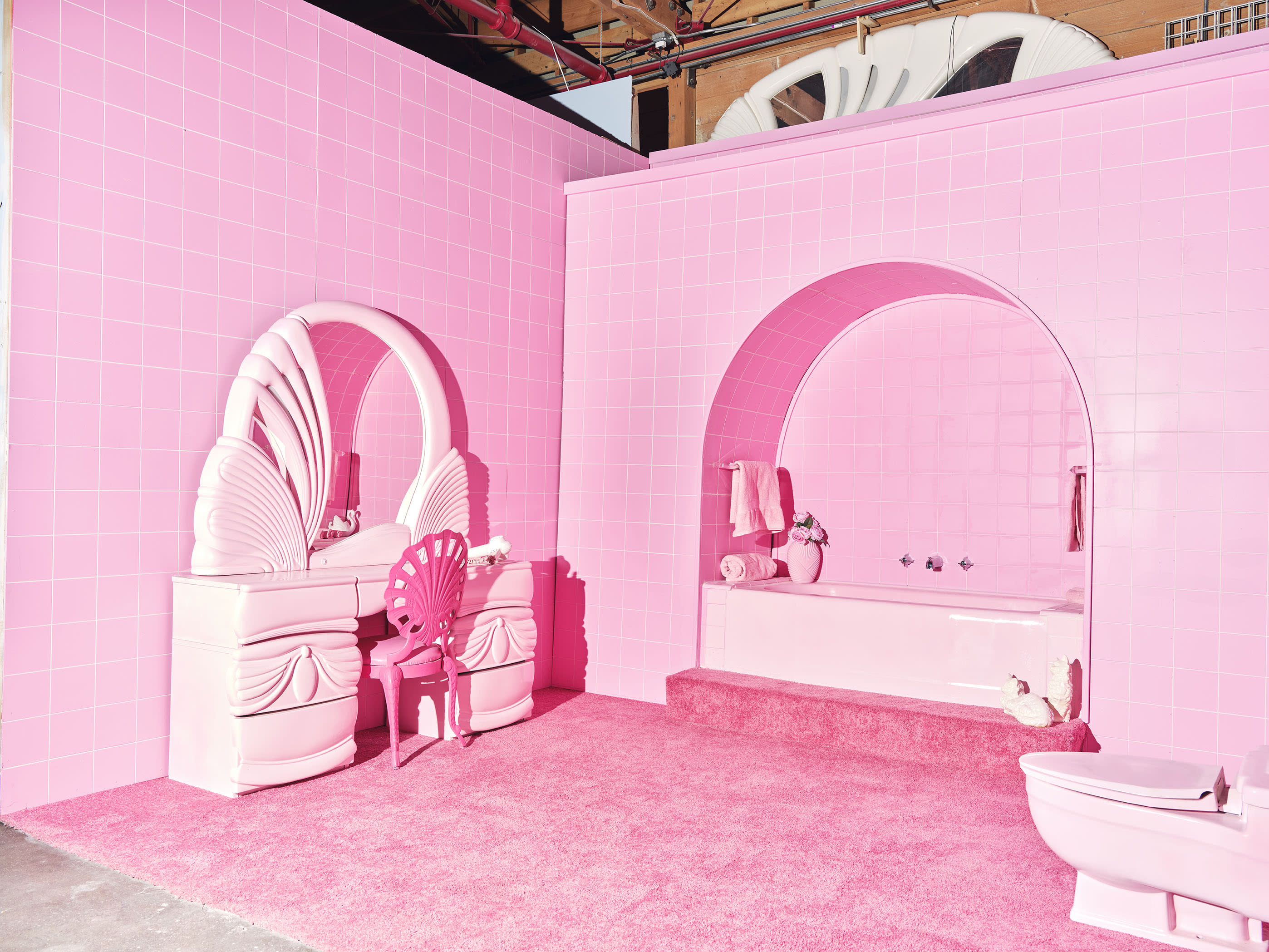 A short film is being shot in a bright pink bathroom featuring a bathtub, decorative elements, and a seated figure.