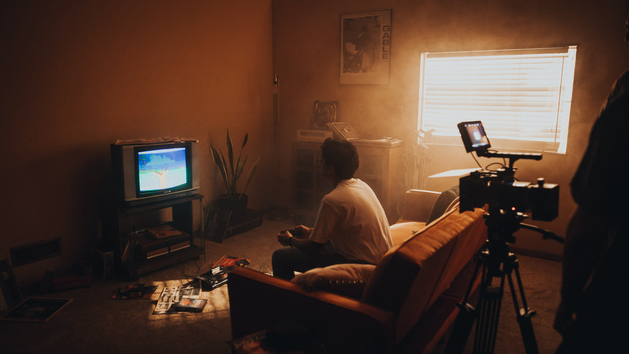 A videographer is capturing footage of a subject in a studio setting with a black backdrop and lighting equipment.