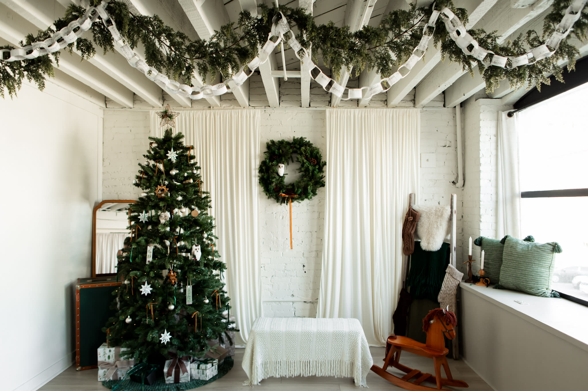 A family poses together for a photo shoot in a bright, decorated room with a small Christmas tree.