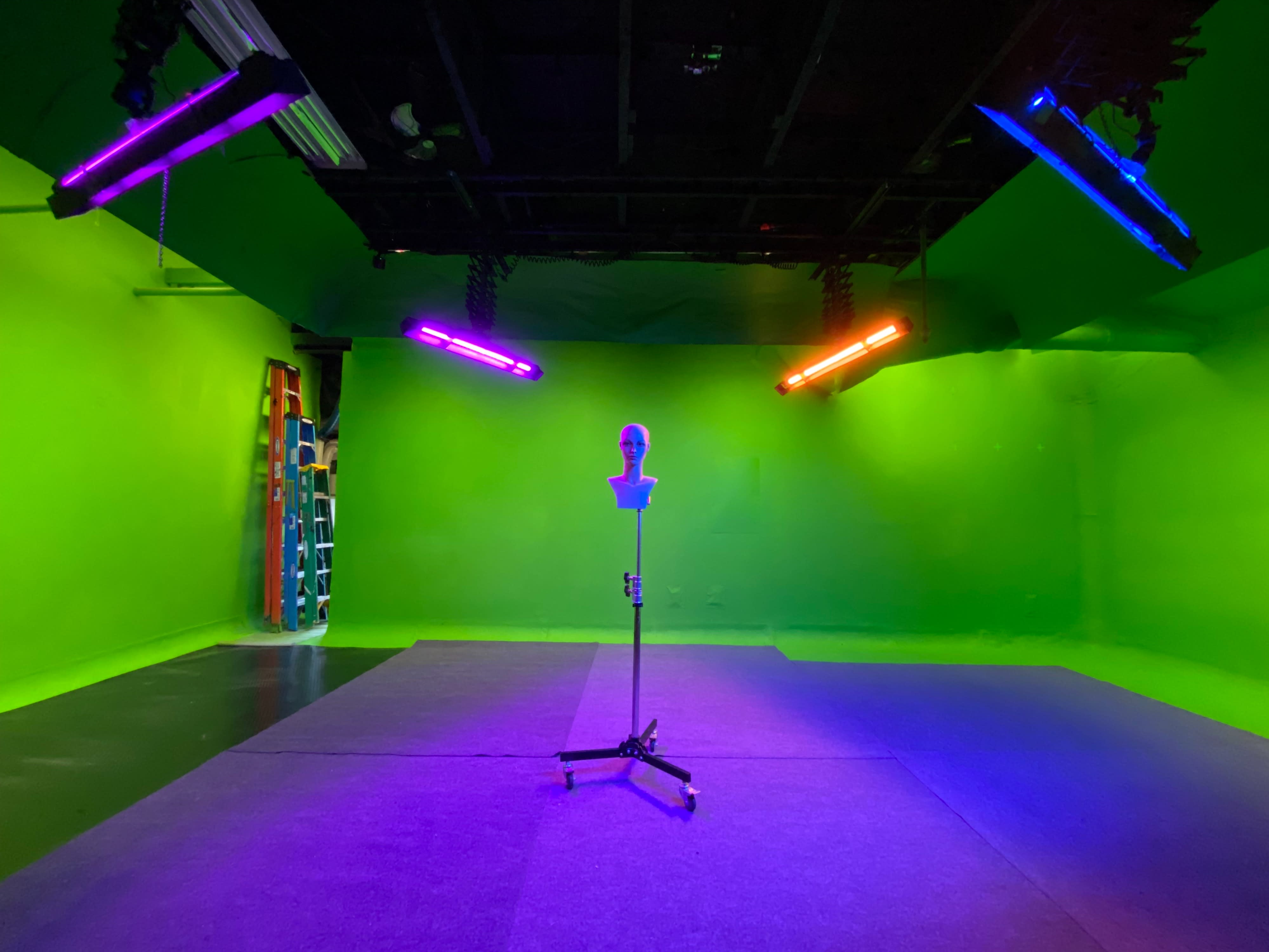 A person in a white lab coat presents a chart with a radiation symbol during a music video shoot in front of a green screen.