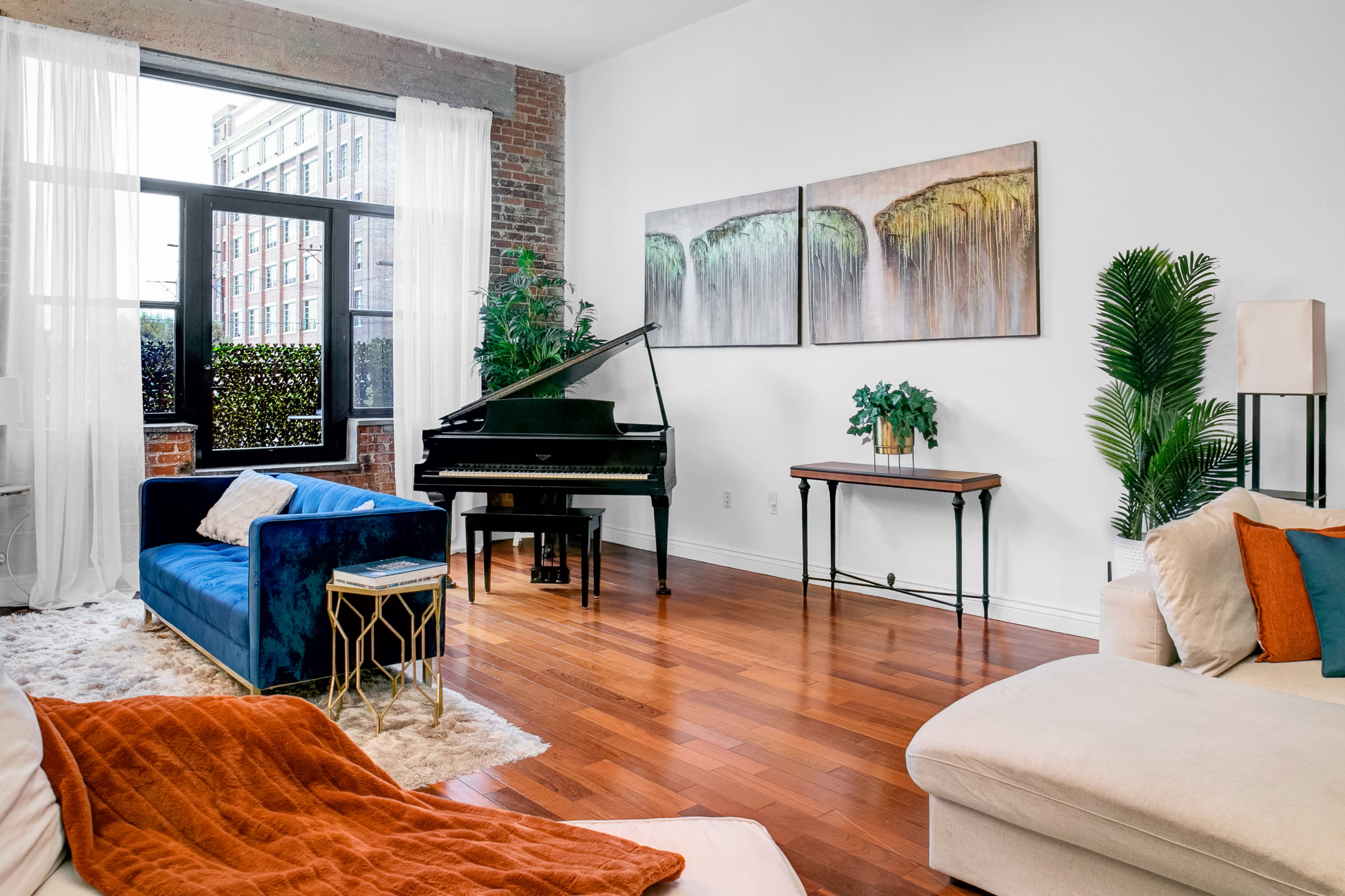 A man plays the piano in a well-lit urban living space adorned with plants and stylish furniture.