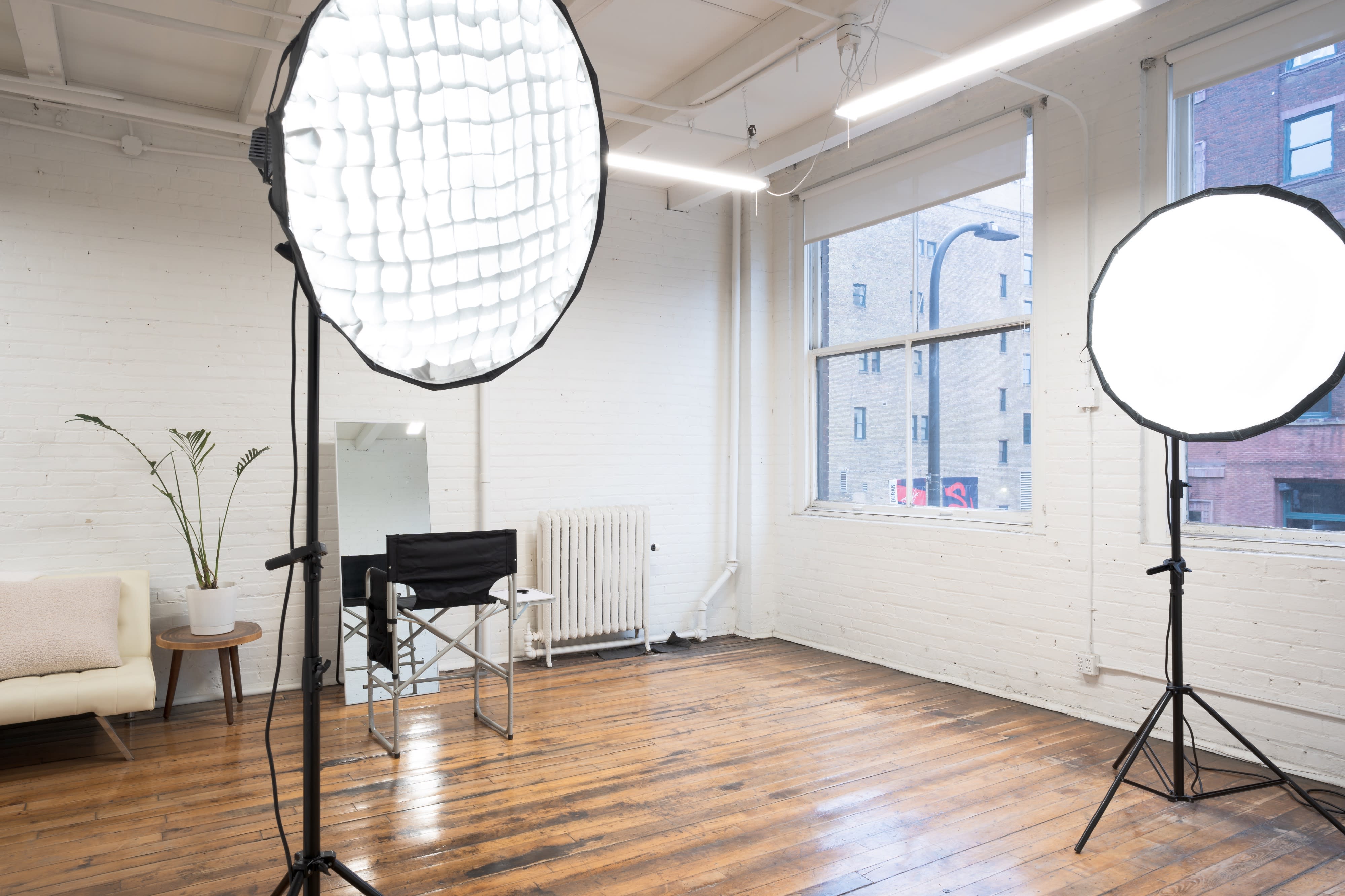 A photographer is taking pictures of a black t-shirt laid out on a white backdrop in a studio setting.