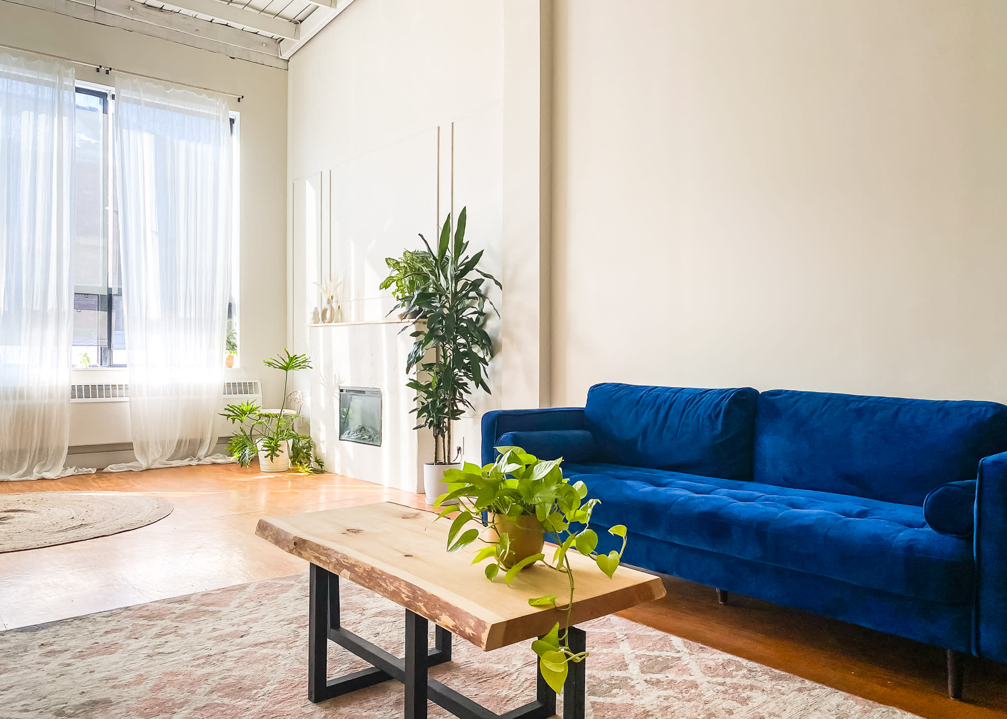 A video shoot takes place in a bright room where a crew captures a conversation between an elderly couple seated on a blue sofa.