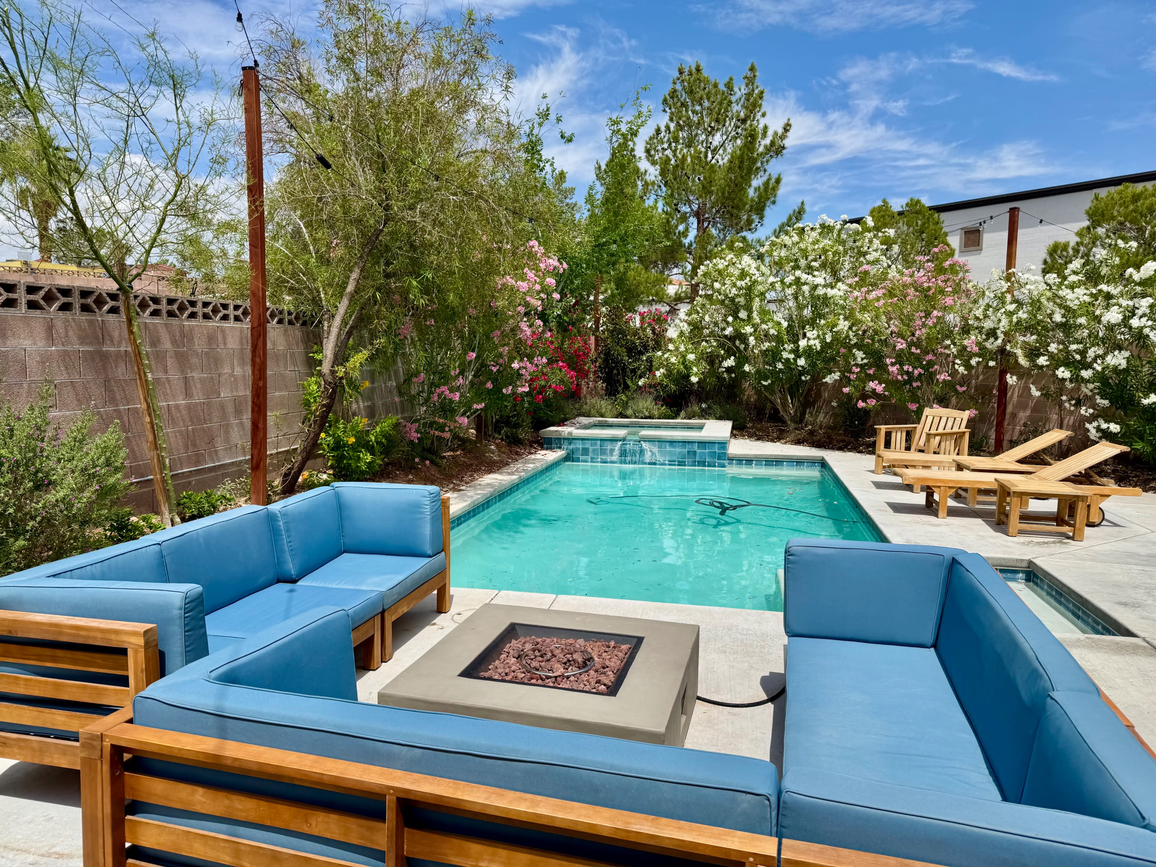 A person pours a beverage into a glass while another individual jumps joyfully by the pool in the background.