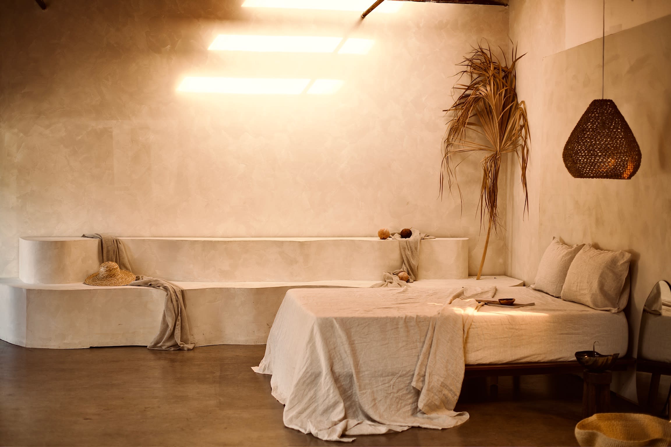 The scene features a minimalist interior with a brown curtain draped within an archway beside a tall dried plant.