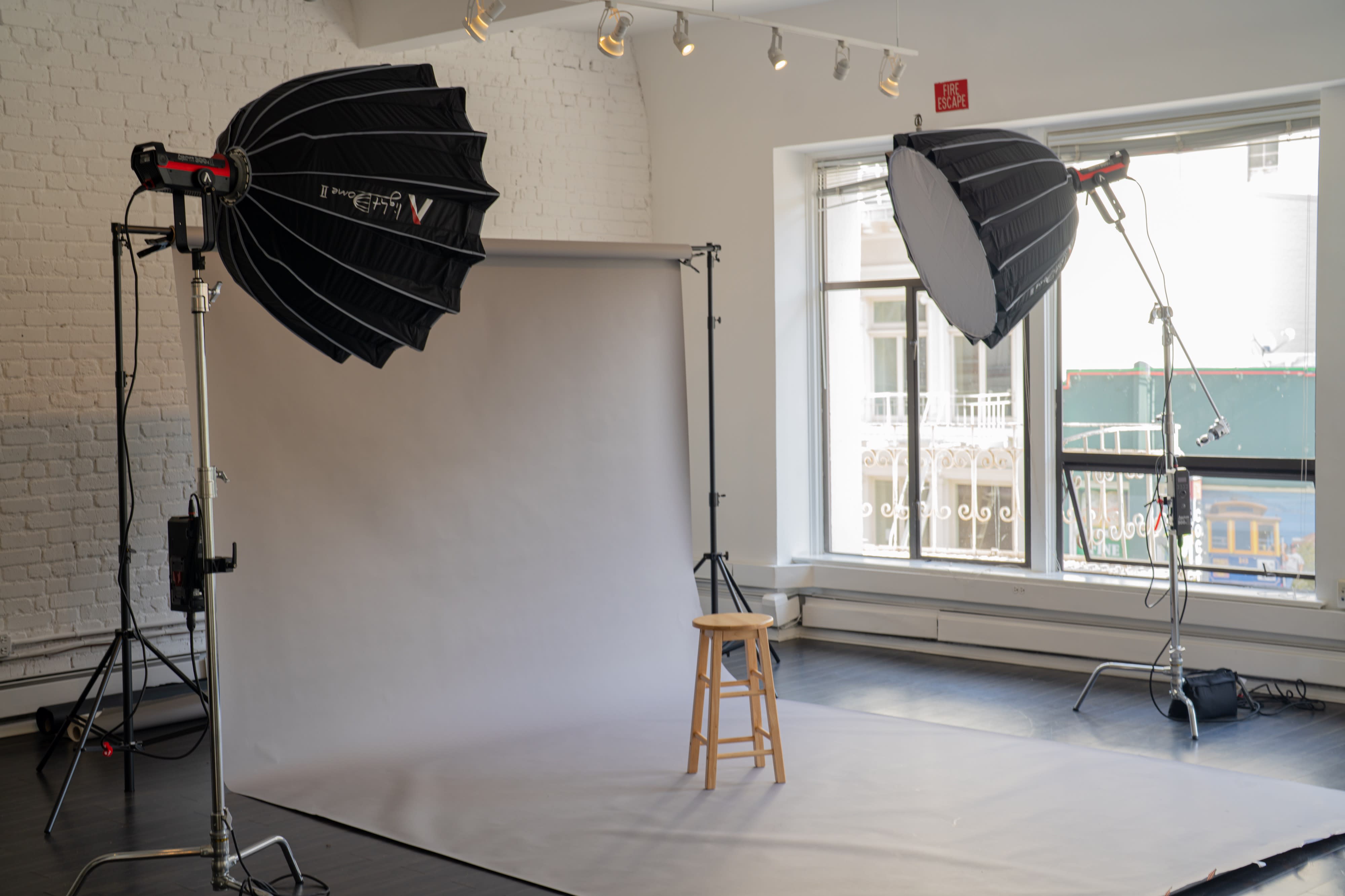 A sit-down interview is taking place in a well-lit studio, featuring two individuals seated on a couch, with cameras and lighting equipment set up to capture the conversation.