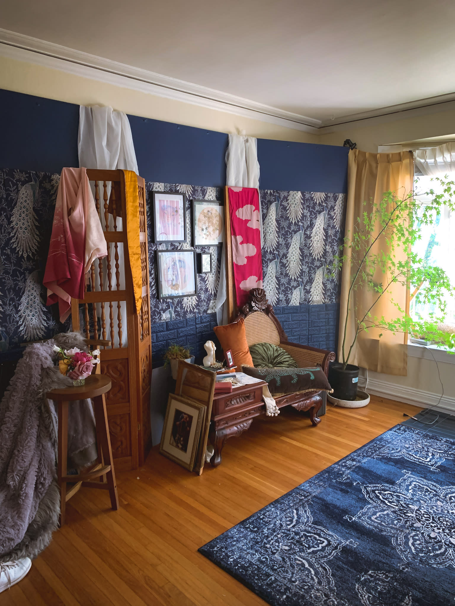 A model poses on a textured rug, leaning forward with her hands on the ground in a softly lit room adorned with colorful pillows.
