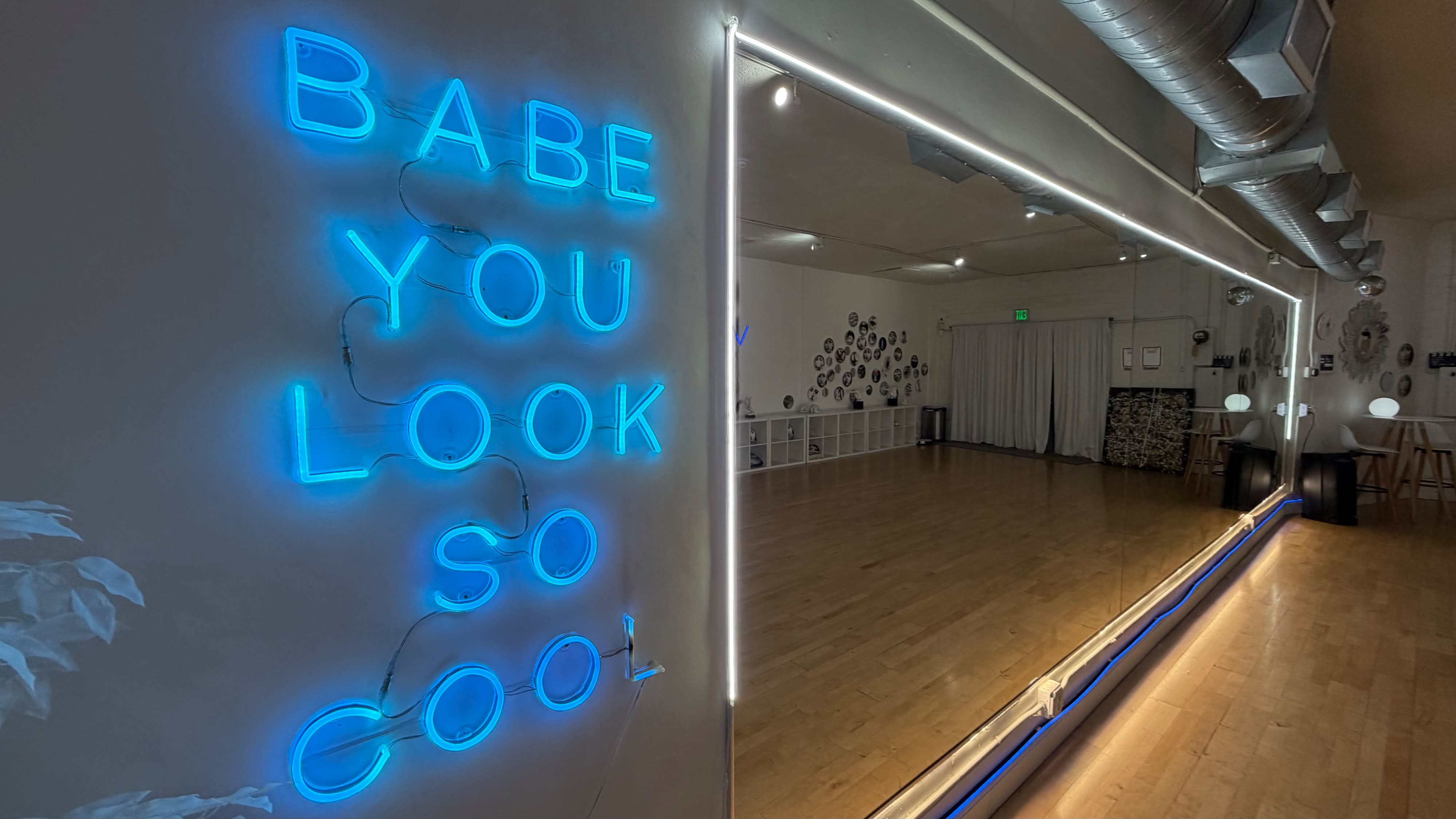 A neon sign displays the message "Babe, You Look So Cool" against a wall.