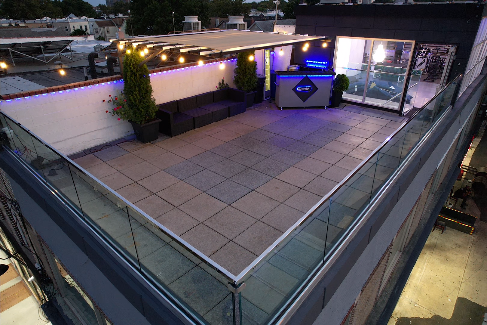 The rooftop event space is set up for a gathering, featuring elegantly arranged tables with floral centerpieces and diningware.
