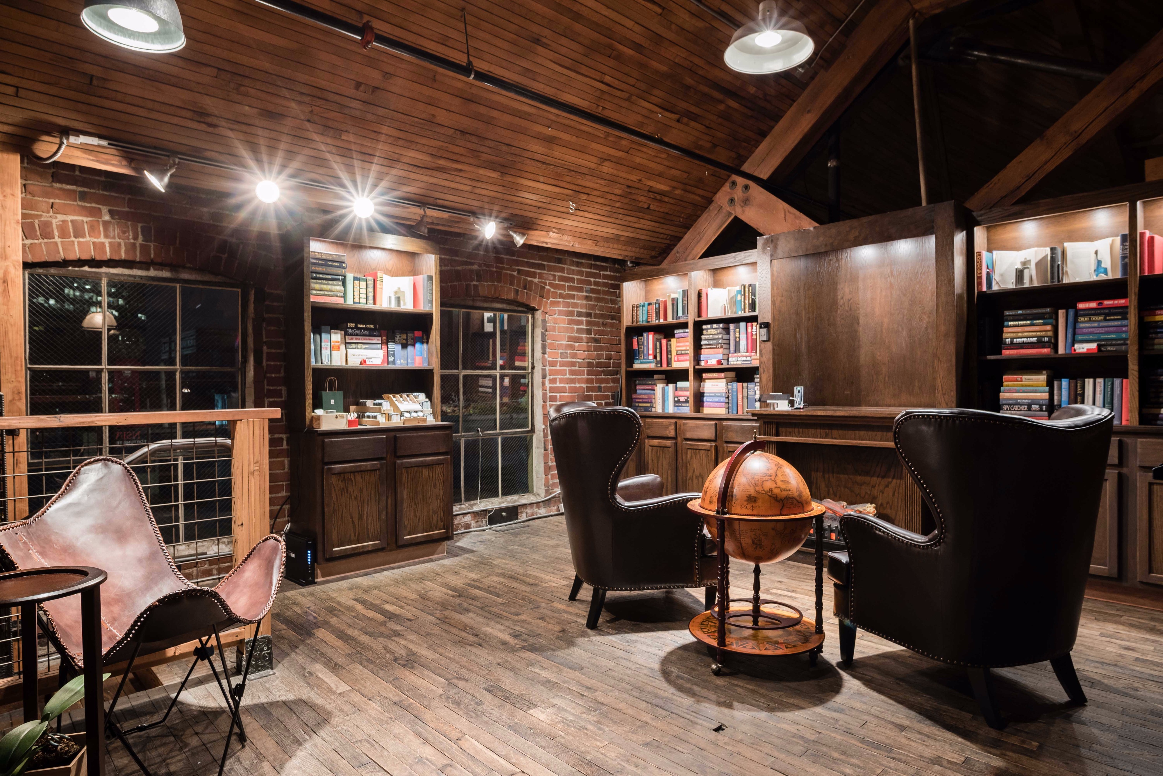 A tailor's mannequin stands in an industrial-style workshop surrounded by wooden furniture and overhead lighting.