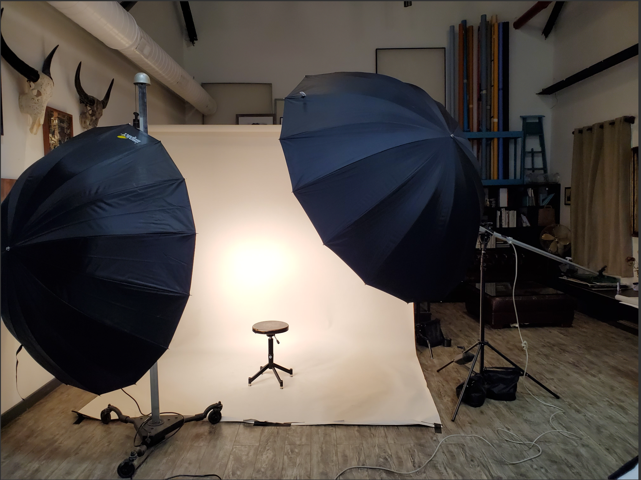 A man sits on a brown leather couch while a camera is positioned in front of him, capturing a scene in a well-organized studio space.