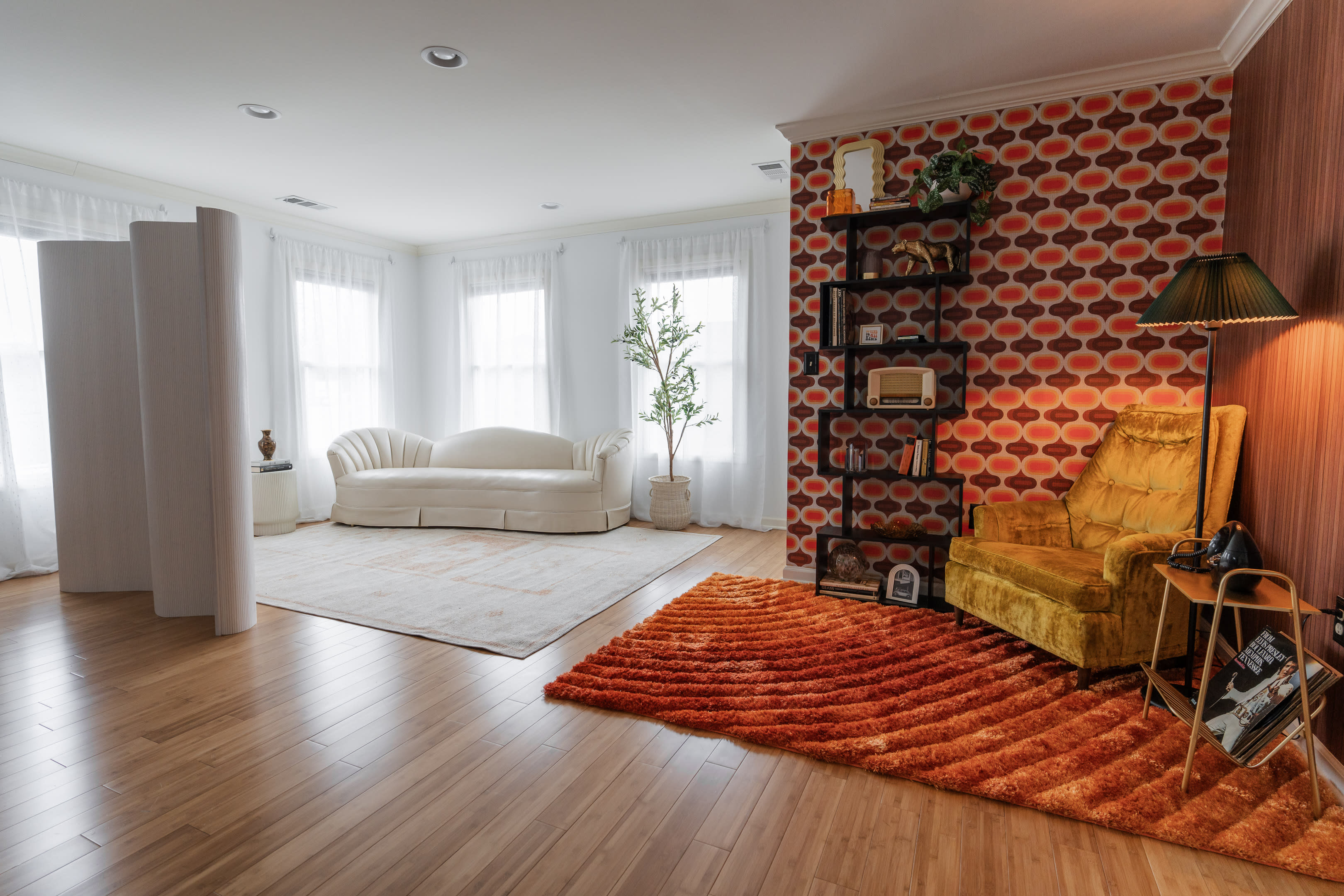 The scene features a photo shoot setup with a vintage armchair, a backdrop of patterned wallpaper, a small Christmas tree, and a lighting stand.