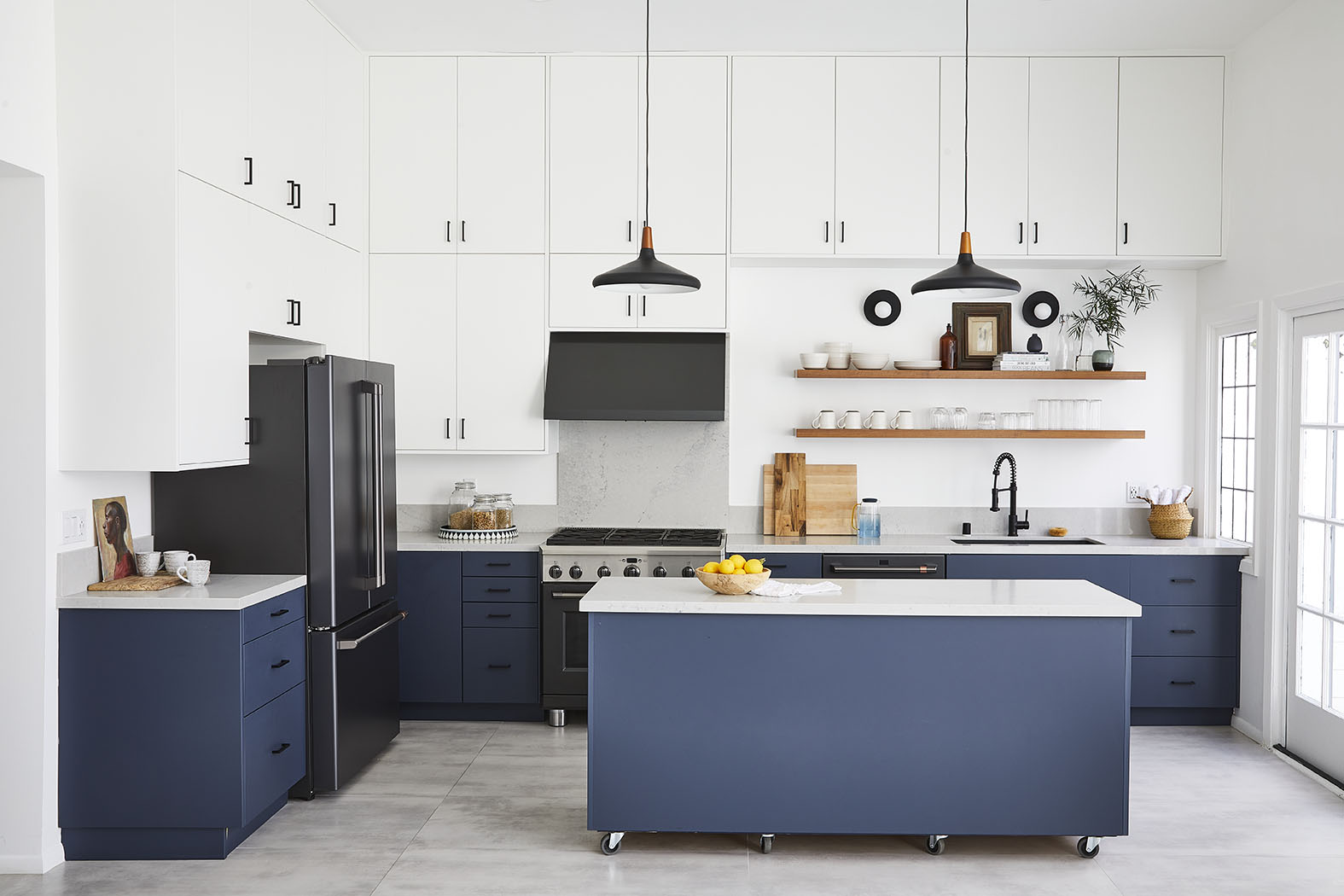 A person stands in a modern kitchen, presenting a colorful array of prepared dishes on a wooden cutting board.