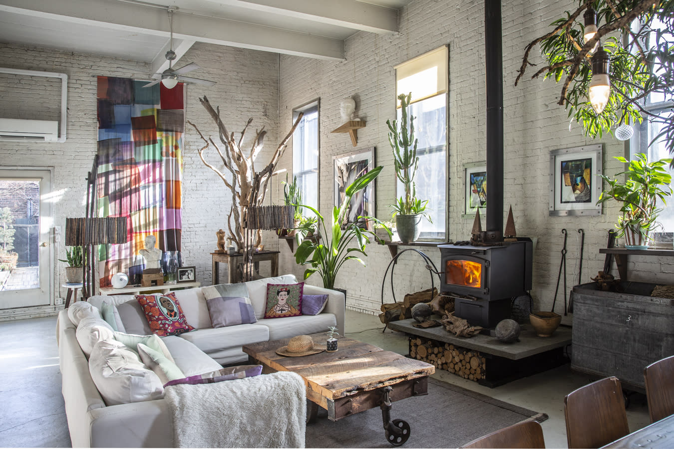 A video interview setup features a camera and lighting equipment on a wooden table in a bright, spacious room with a couch and artwork.