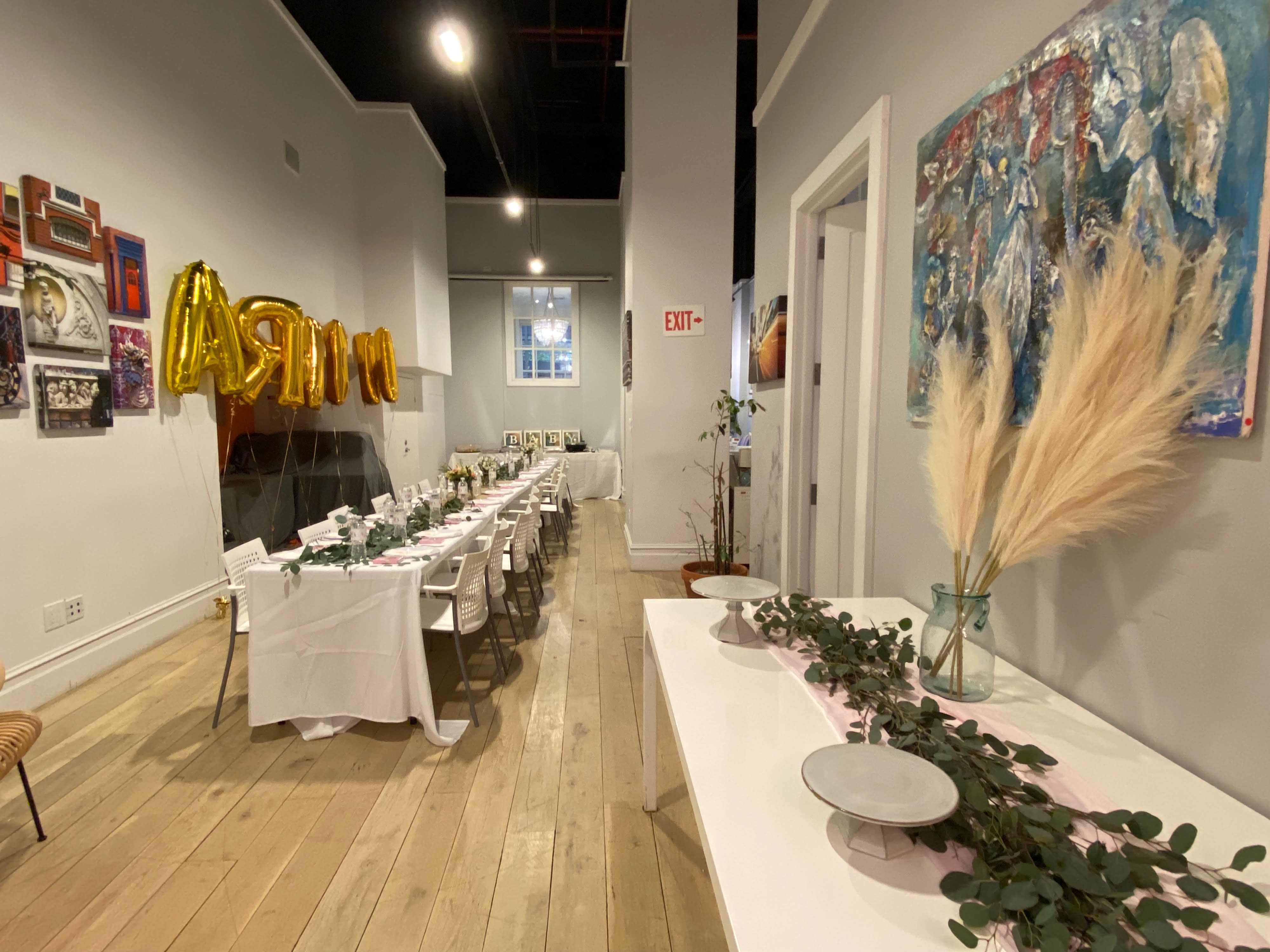A long table is set with golden plates and clear glasses, preparing for a surprise birthday party.