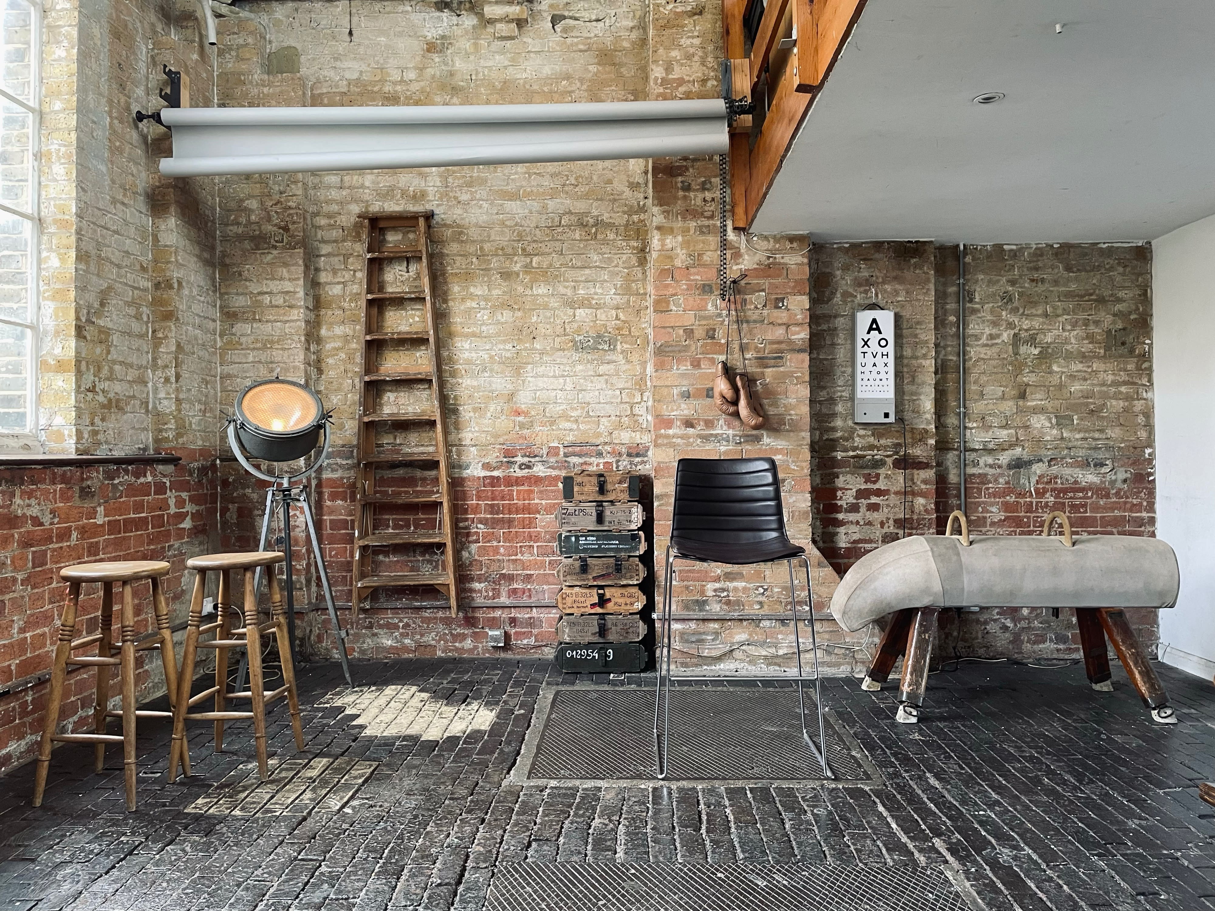 The image shows a photography studio setup featuring a backdrop, lighting equipment, and various props arranged on a wooden floor.
