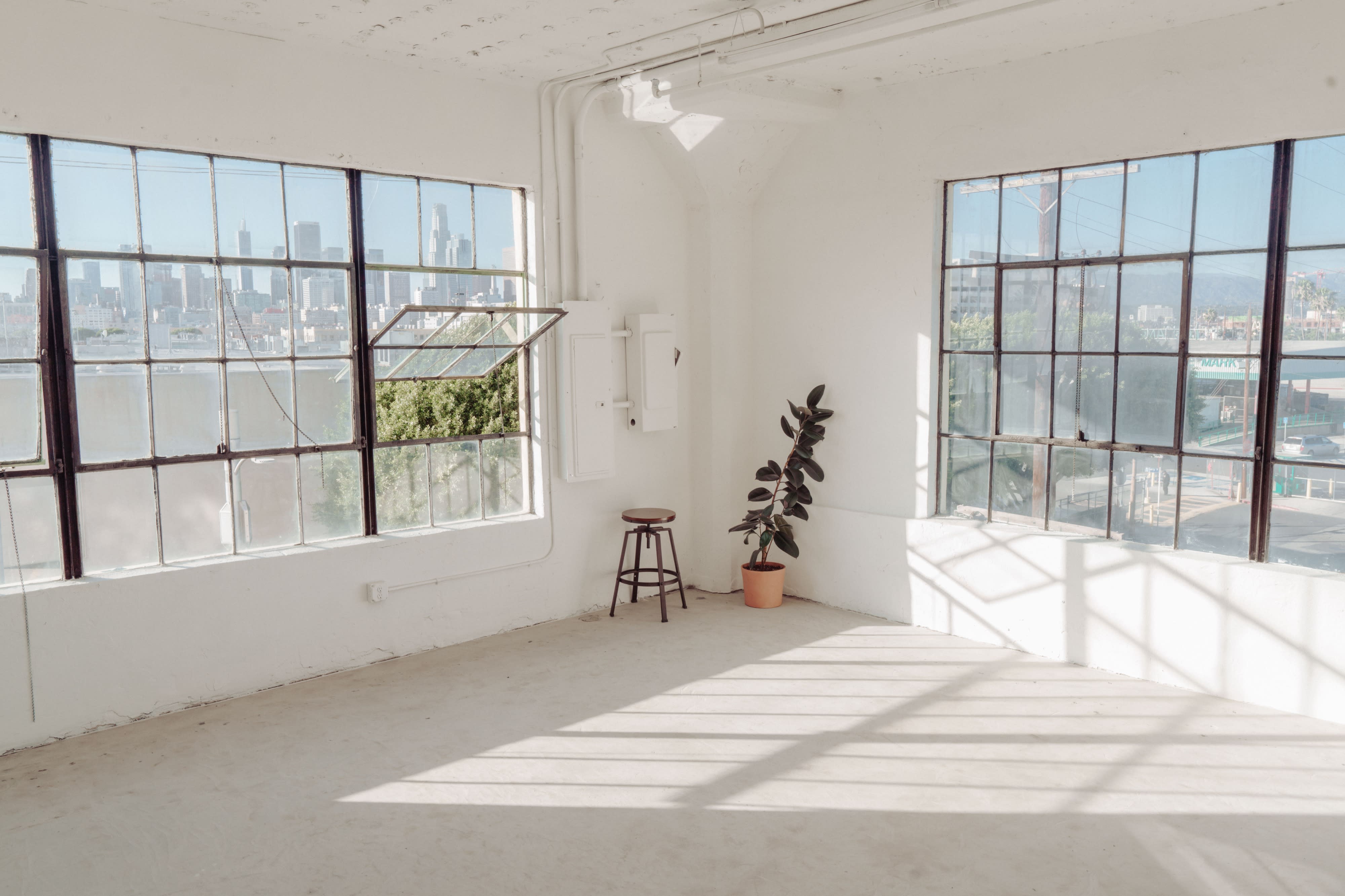 A pregnant woman and her partner share a tender moment during a photoshoot in a bright, spacious room.