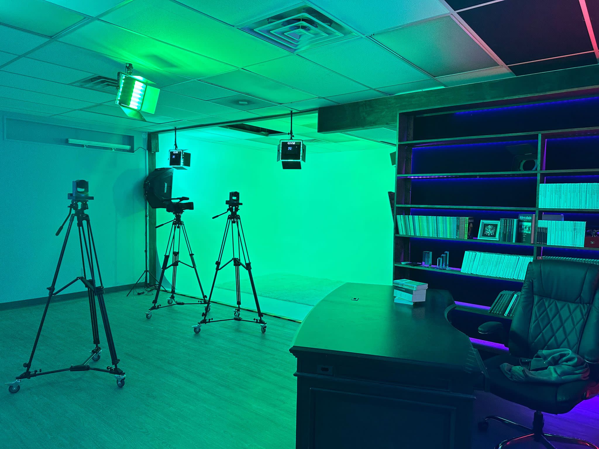 A video shoot is set up in a room with red lighting and a red backdrop.