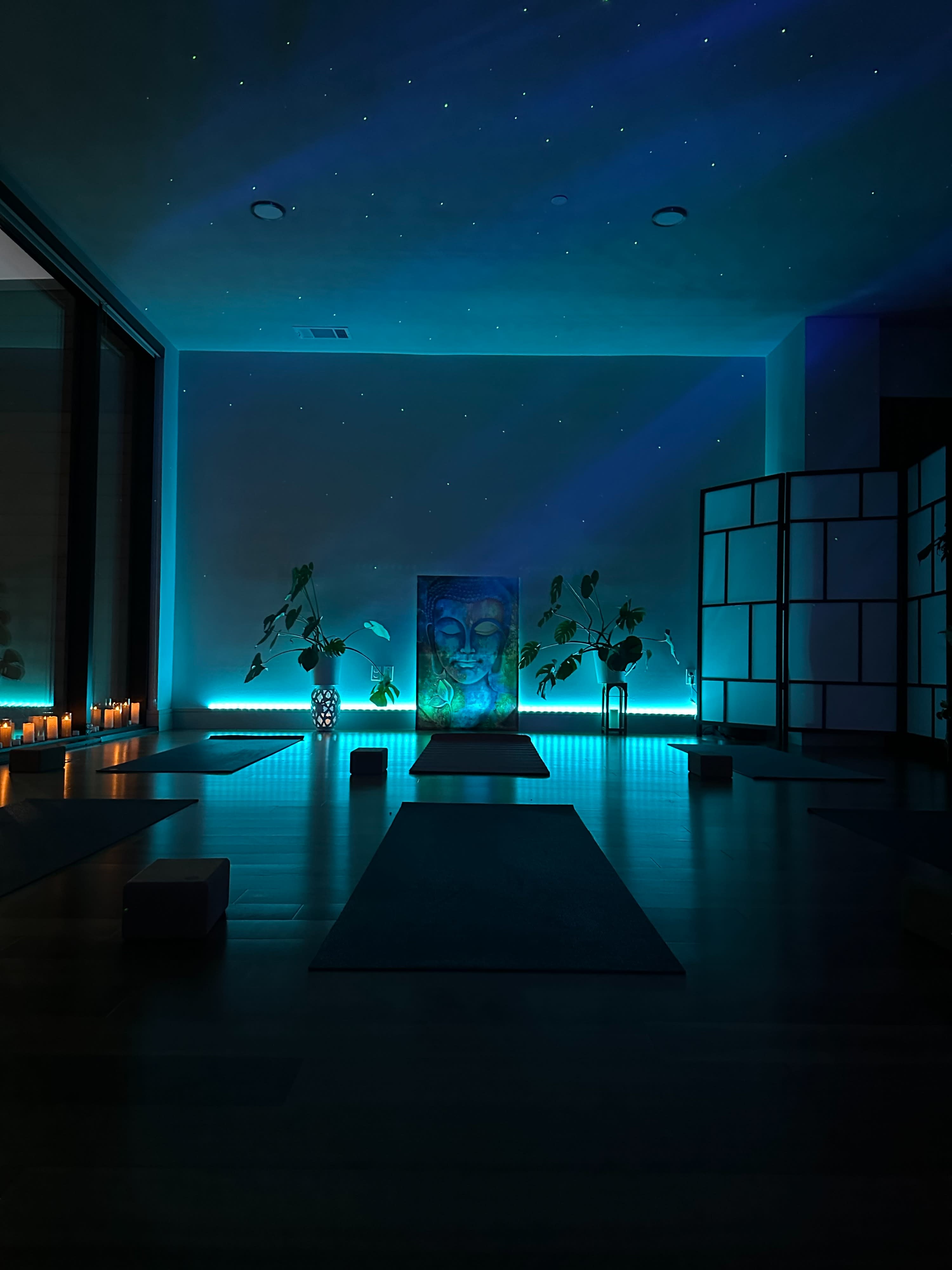 The image shows a serene sound bath setup with circular arrangements of cushions on mats, surrounded by plants and a decorative screen.