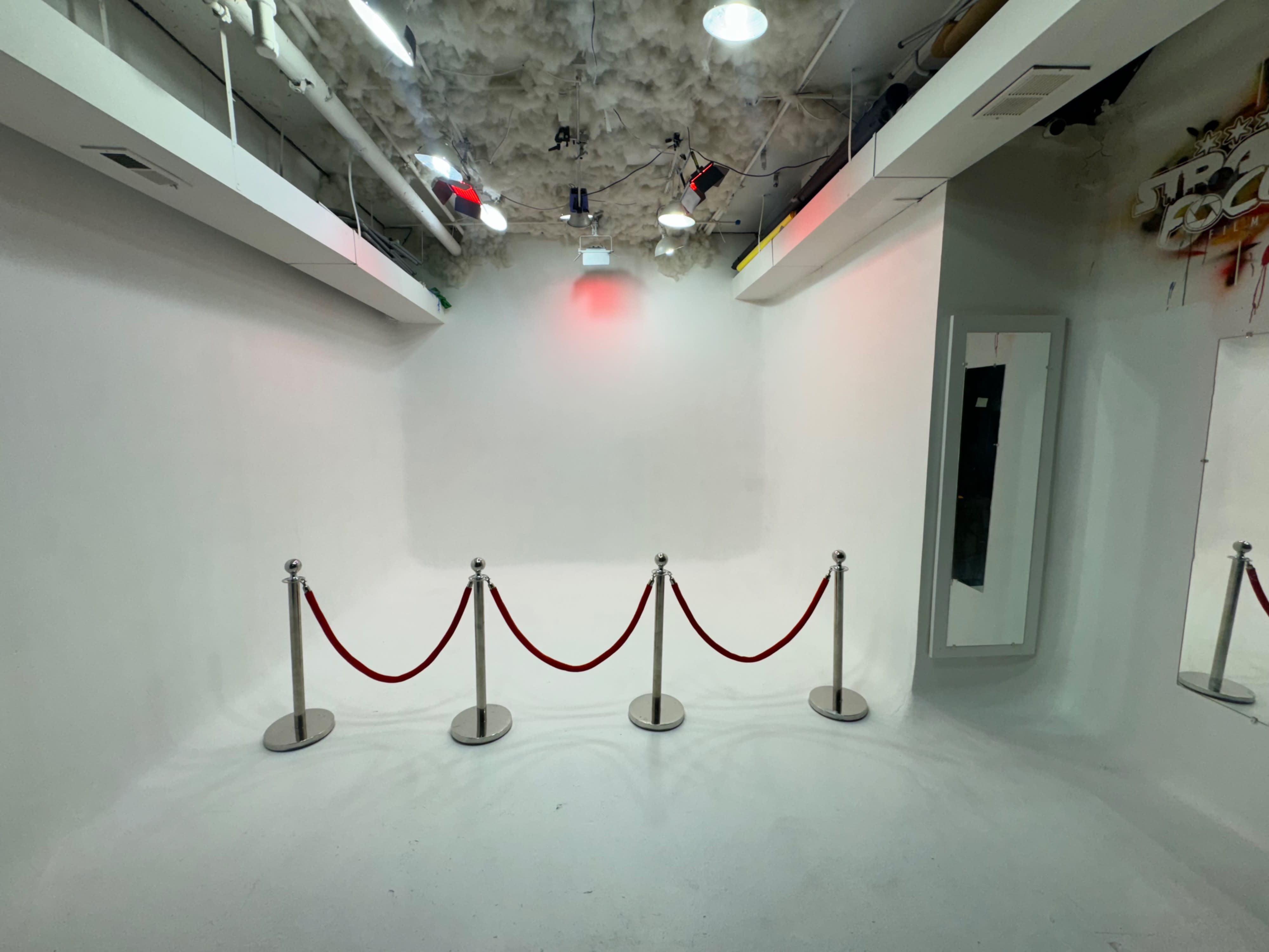 A person stands in a blank studio space near a microphone on a stand while being filmed.