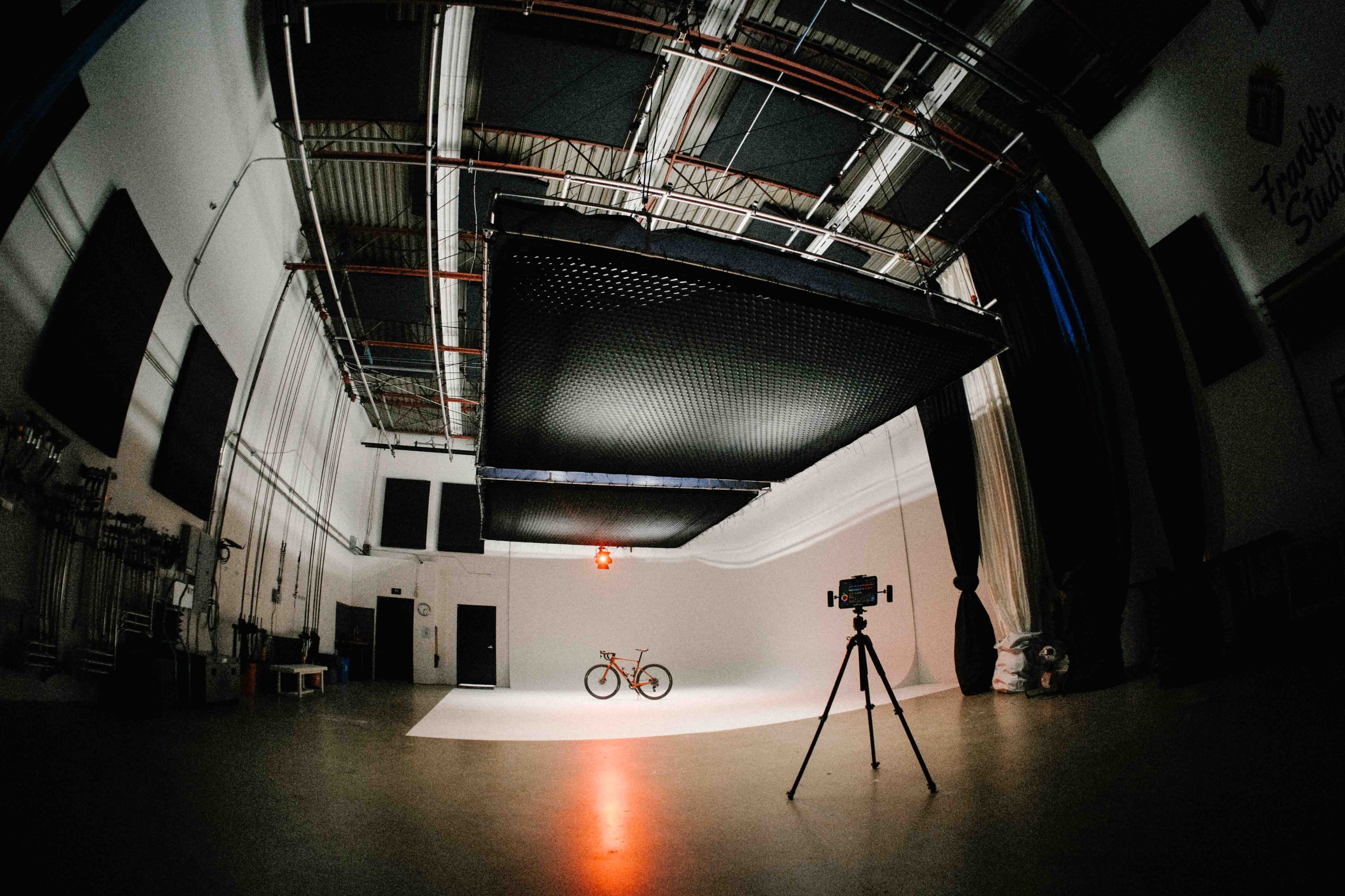 A photographer captures a model posing on a chair in a studio setting.