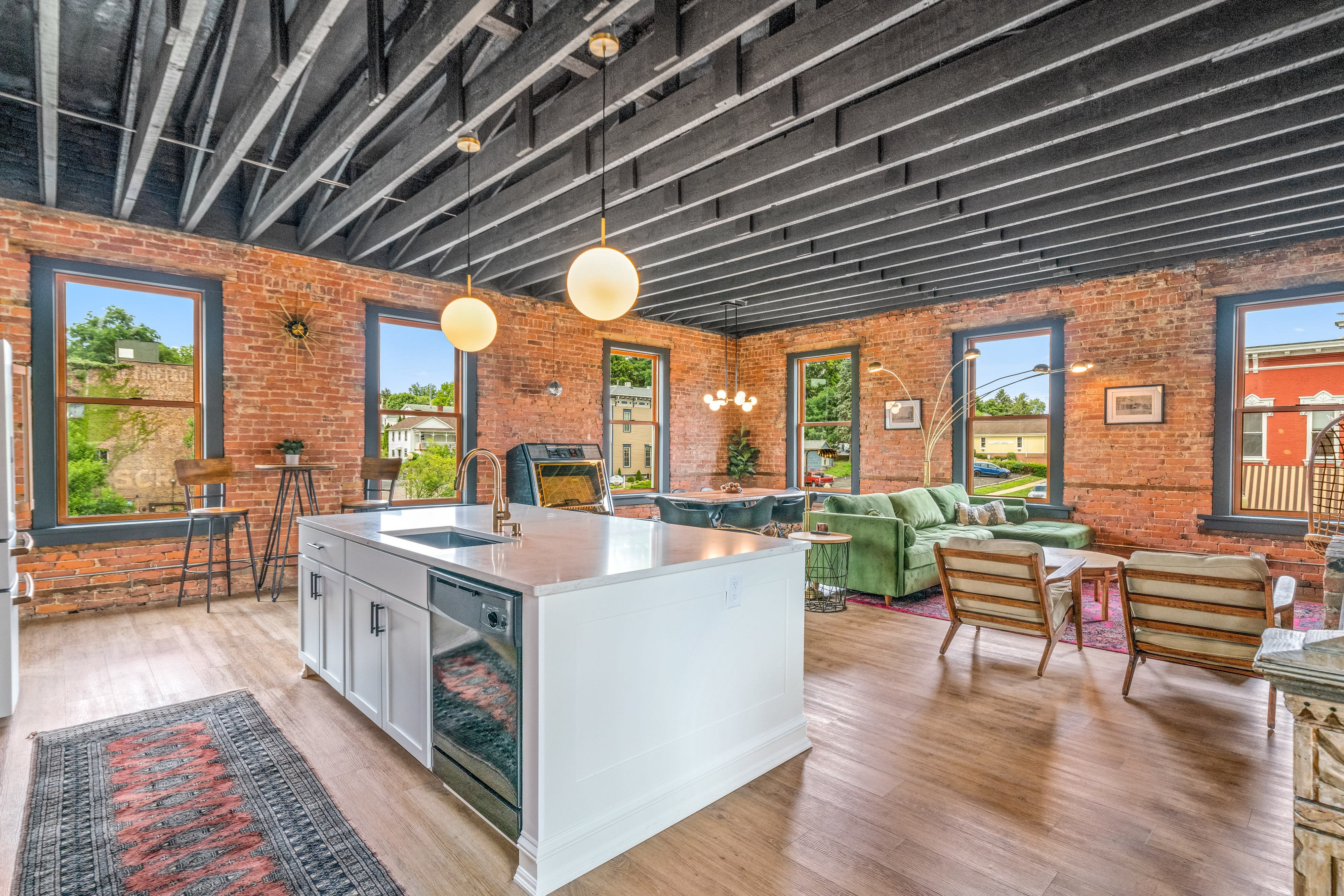 A family poses together on a bed in a cozy, well-lit room with exposed brick walls.