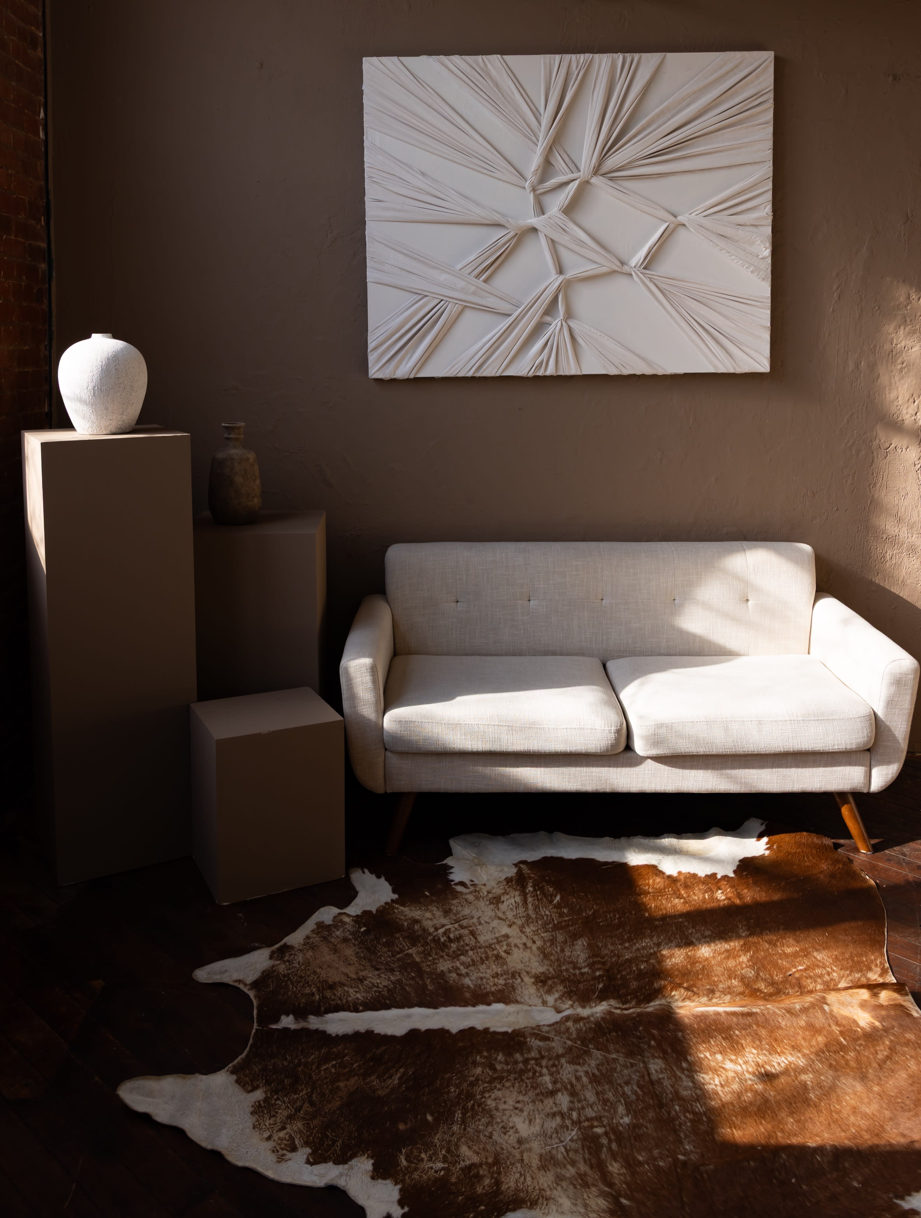 Two models pose seated on a cowhide rug surrounded by lit candles in a styled indoor setting.