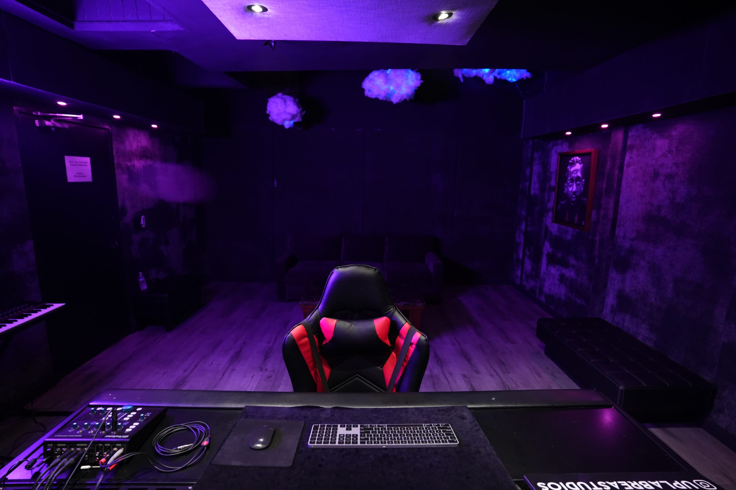 Two men collaborate on music production in a dimly lit recording studio.