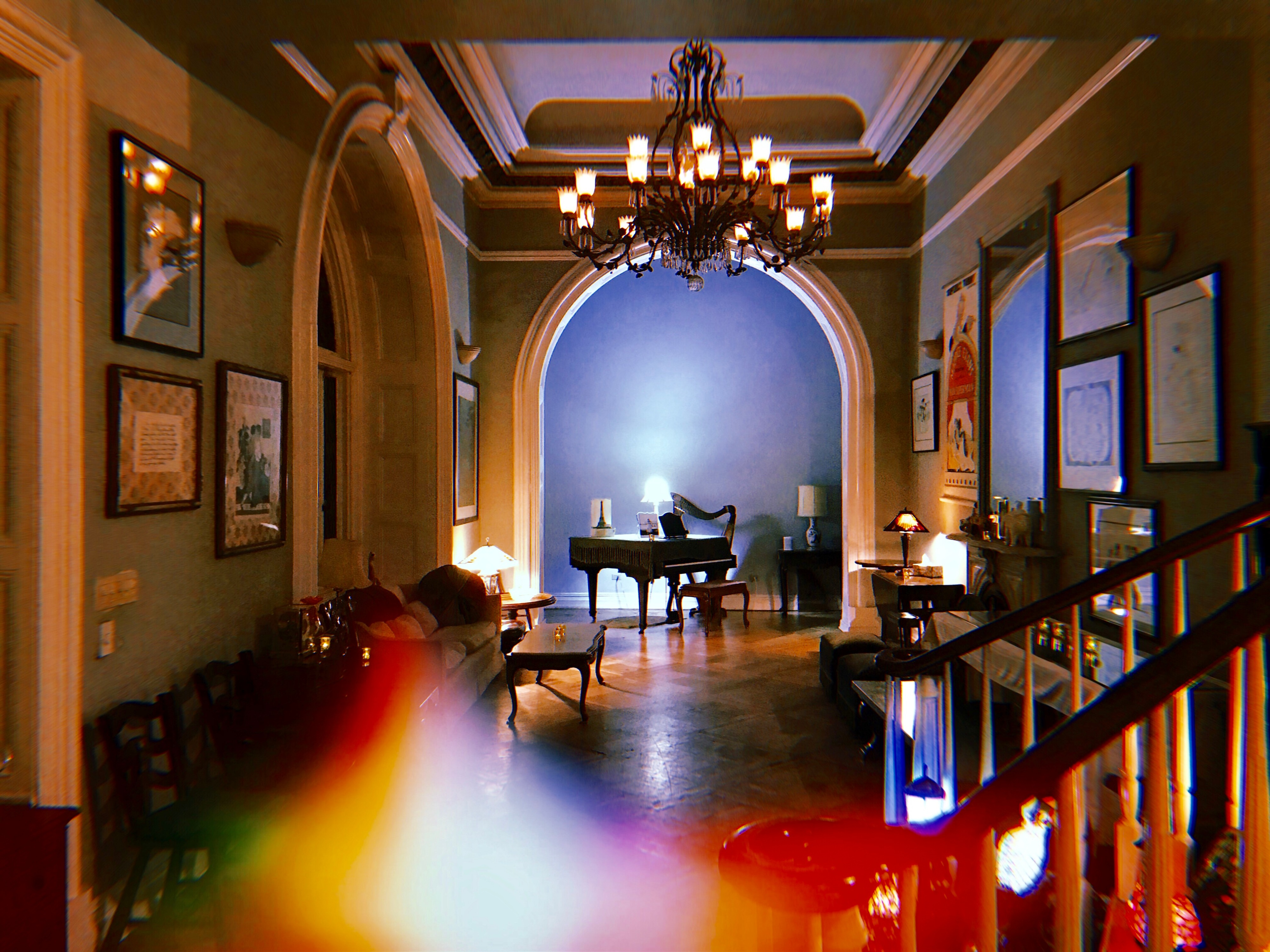 A man kneels in front of a woman, holding out an engagement ring amid a decorated room filled with candles and white balloons.