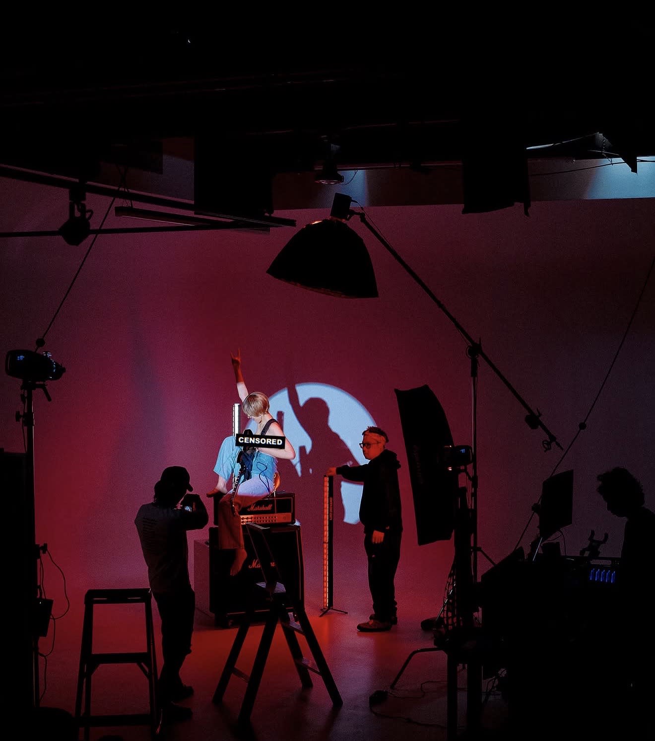 A model poses in a flowing dress against a softly colored backdrop during a test shoot.