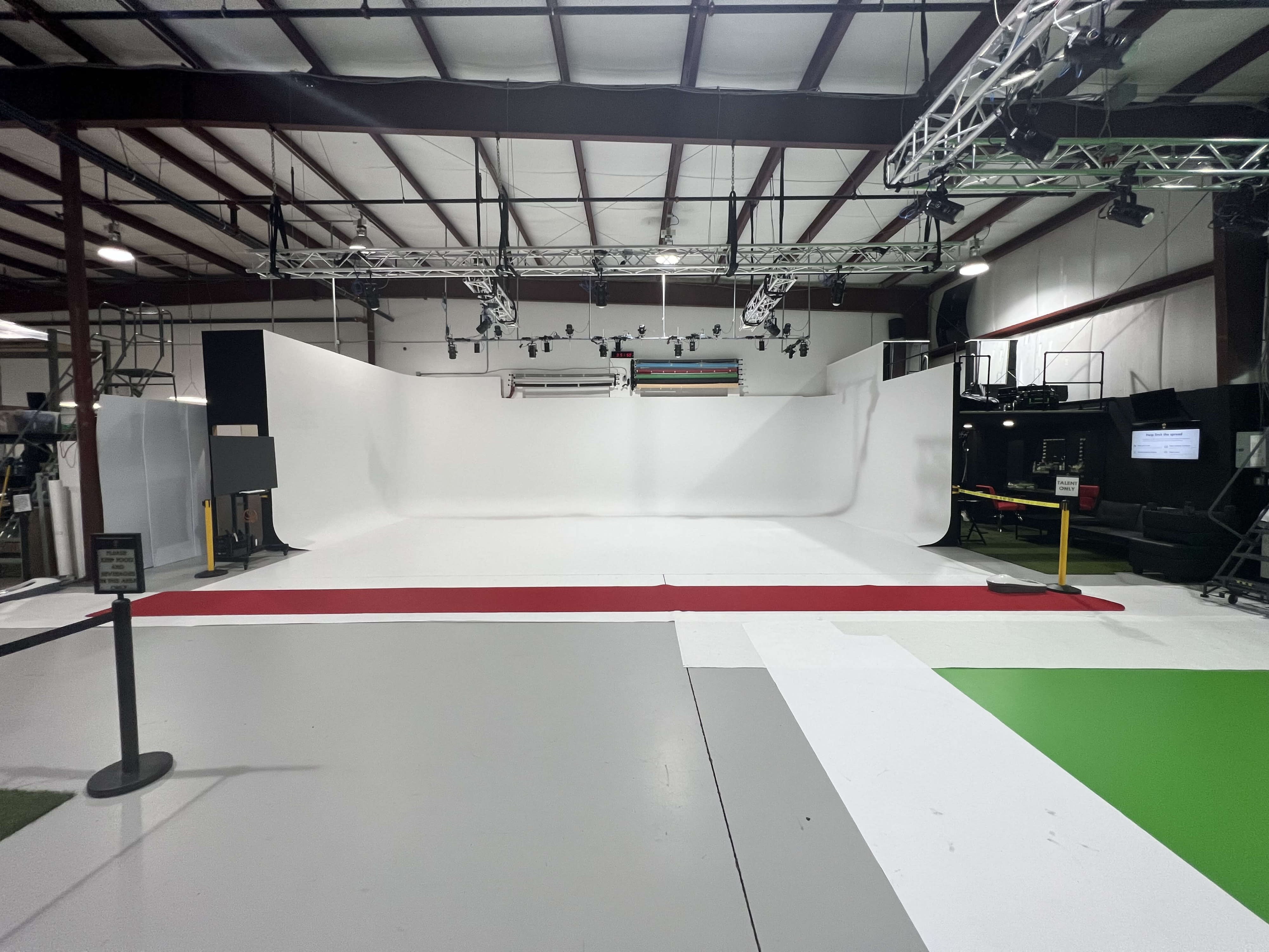 Three individuals collaborate on a music production set within a studio featuring a blank backdrop and studio lighting.