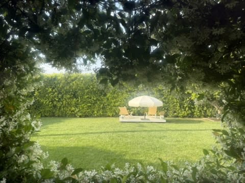A couple stands hand in hand during their wedding ceremony in a garden setting, with a banquet table set nearby.