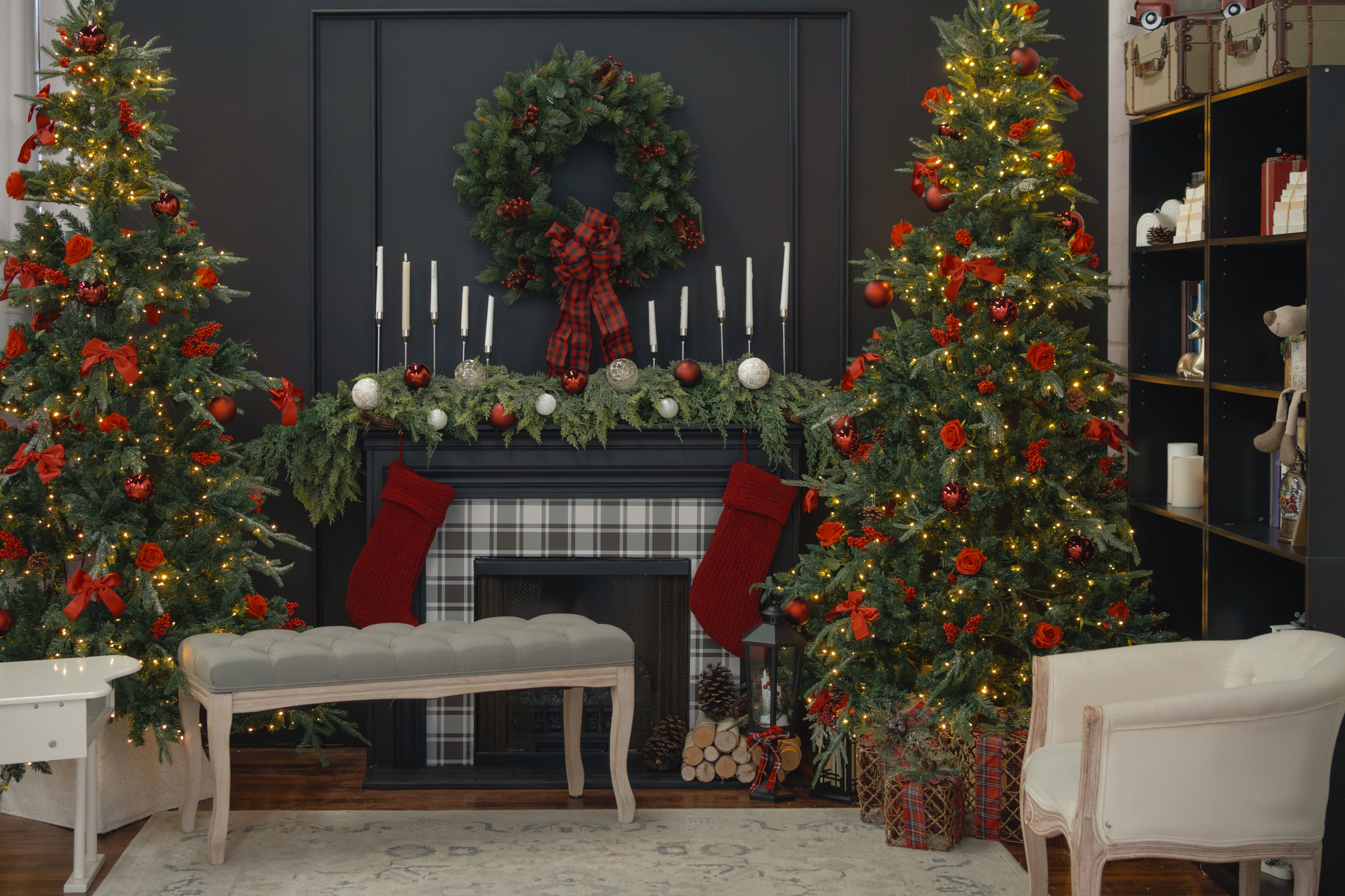 A family poses for a photoshoot on a sofa decorated for the holidays, with the parents dressed in festive attire and holding their smiling baby.