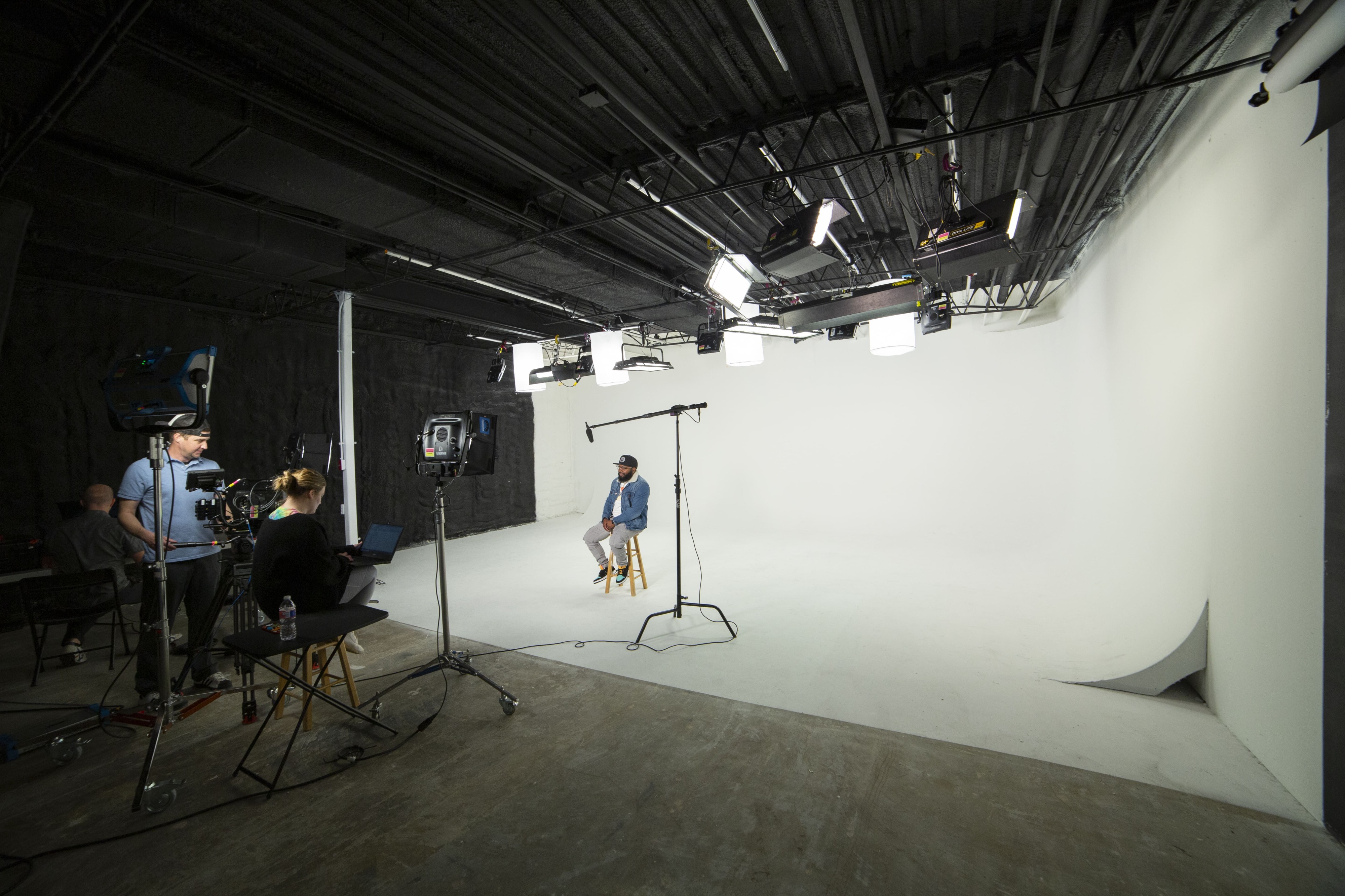 A person poses in a studio wearing a graphic t-shirt and flame-patterned shorts while looking down.