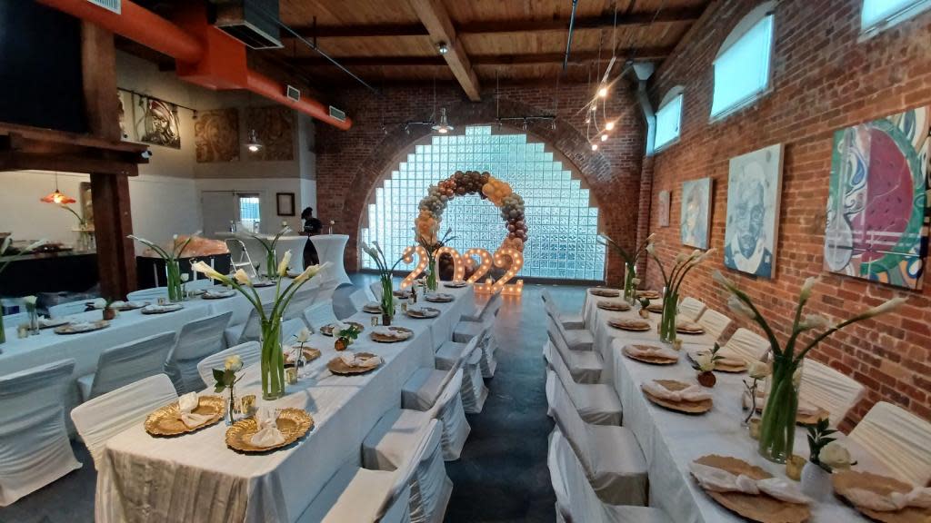 A wedding reception setup features a beautifully arranged table with candles and floral arrangements against a backdrop of glass block windows.