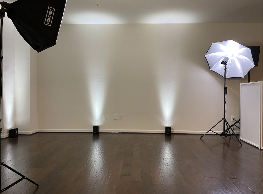 A videographer records models posing under red lights in an indoor setting.