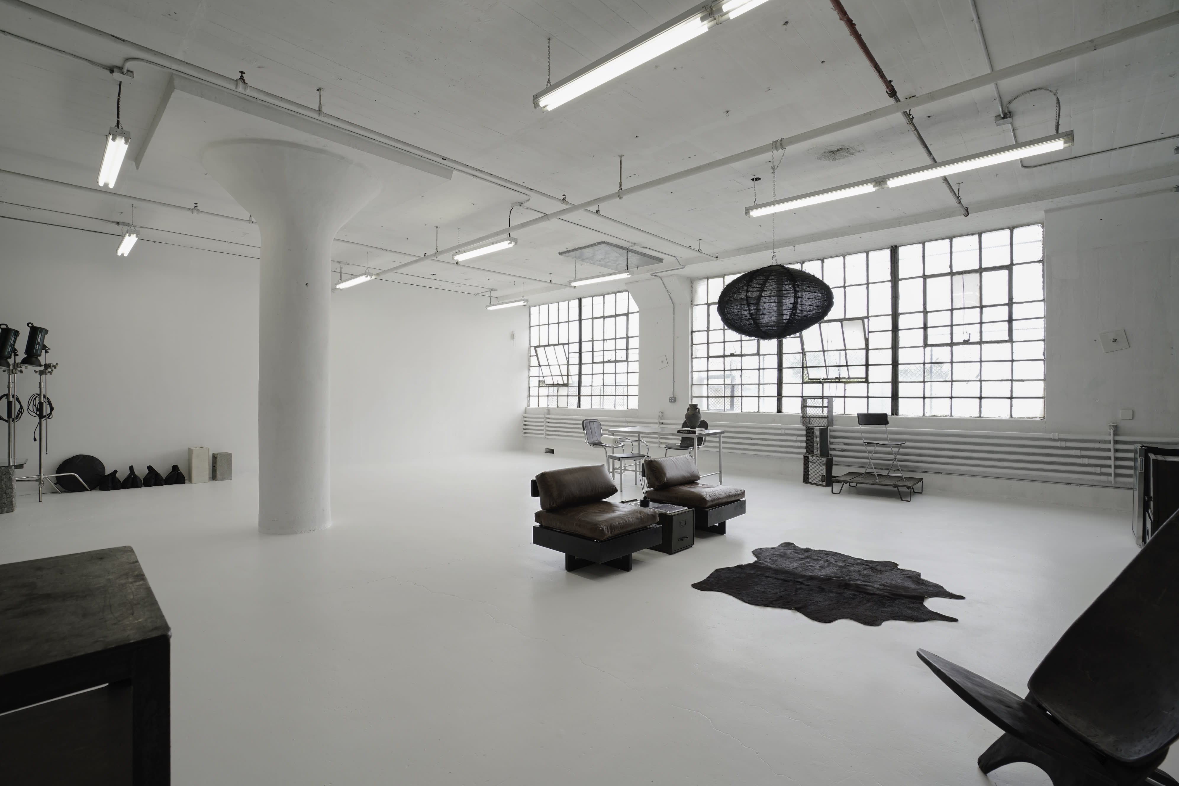 A film crew is setting up equipment for a shoot in a spacious studio with large windows.