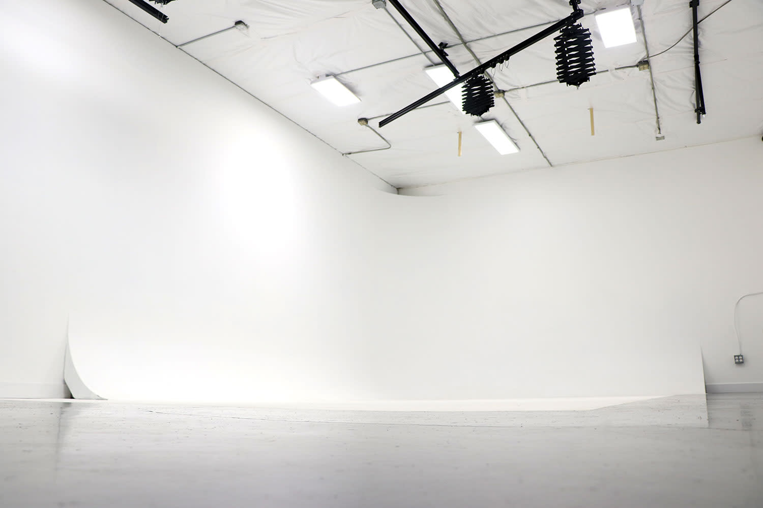 A person stands in front of a camera in a well-lit studio while another individual operates the camera equipment.